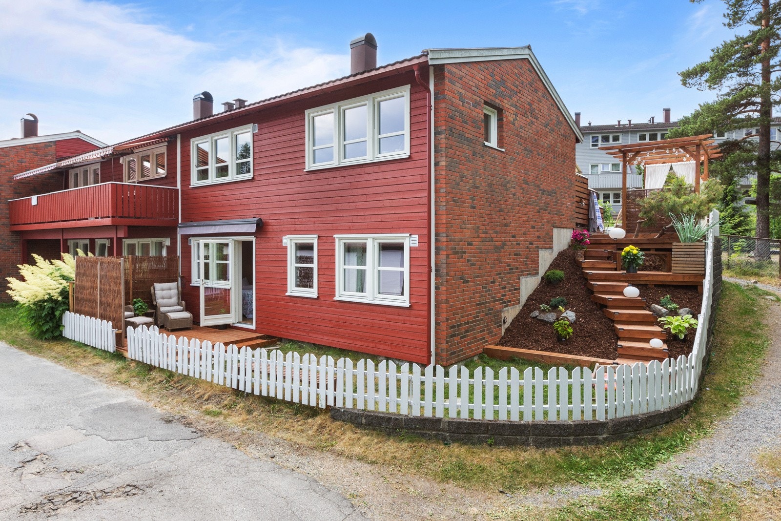 Baksiden har også egen terrasse og beplantning. Her er utgangen fra soverom og trapp på siden av huset Galleribilde