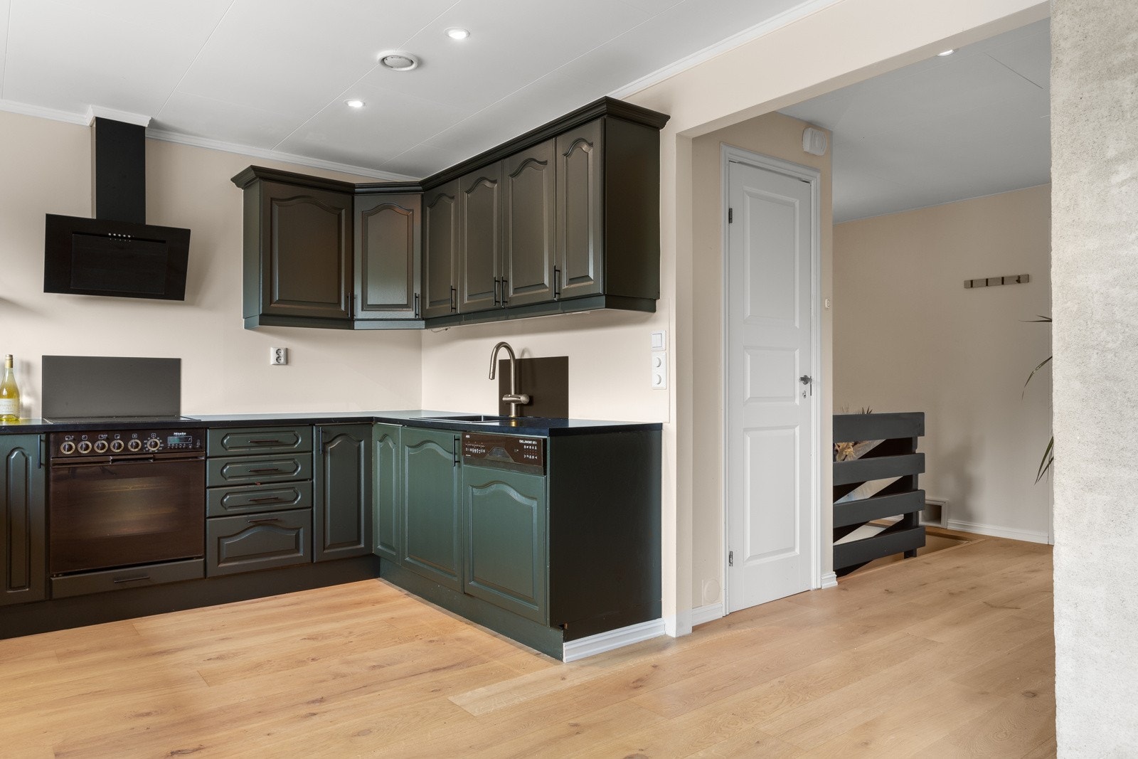 Stort og innholdsrikt U-kjøkken med lange benkeplater og med skap over den ene veggen. Galleribilde