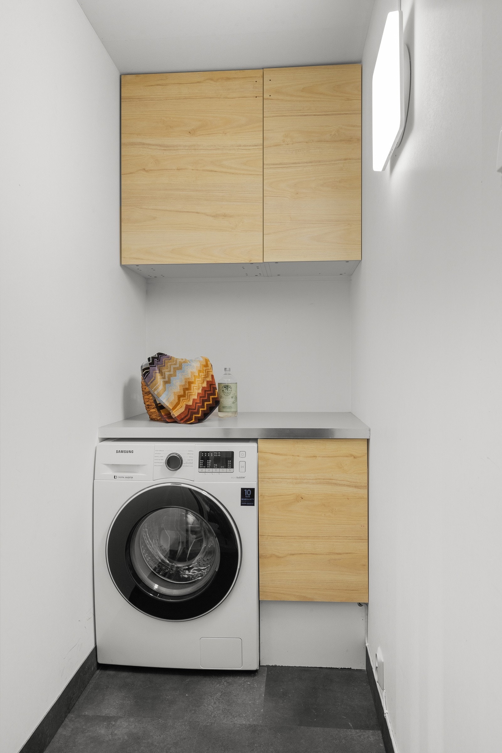 Vegg i vegg med kjøkkenet er det en bod som har fått opplegg for vaskemaskin med benkeplate over. Galleribilde