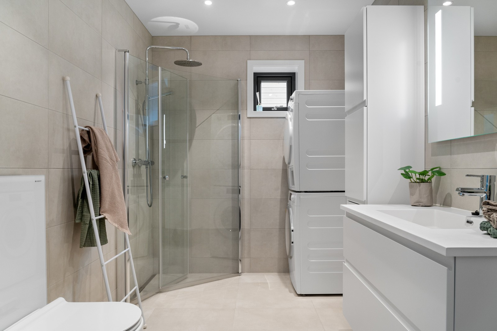 Badet er flislagt med stort dusjhjørne og god plass for vaskemaskin og tørketrommel.