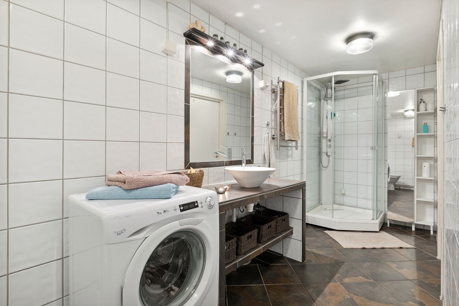 Badet er innredet med toalett, plassbygd innredning med servant, dusjkabinett og opplegg for vaskemaskin. Galleribilde