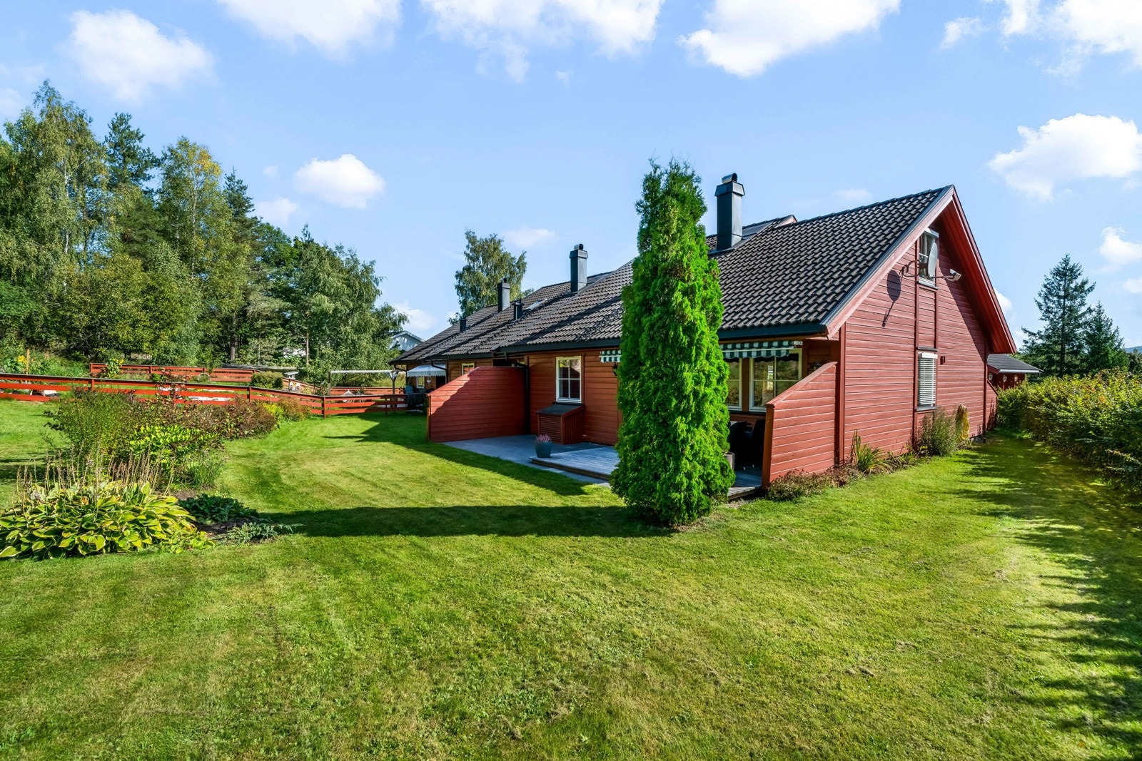 Stor hage pent opparbeidet med frodige bed, plen og skjermede uteplasser. Galleribilde
