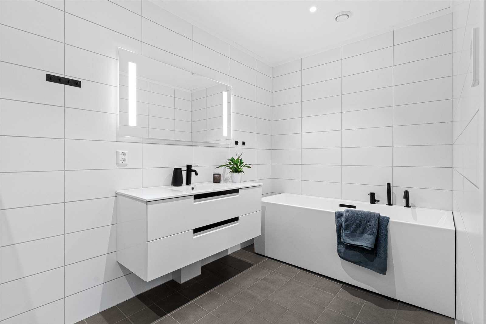 Badet er innredet med servant, badekar, dusjhjørne og veggehengt toalett. Galleribilde
