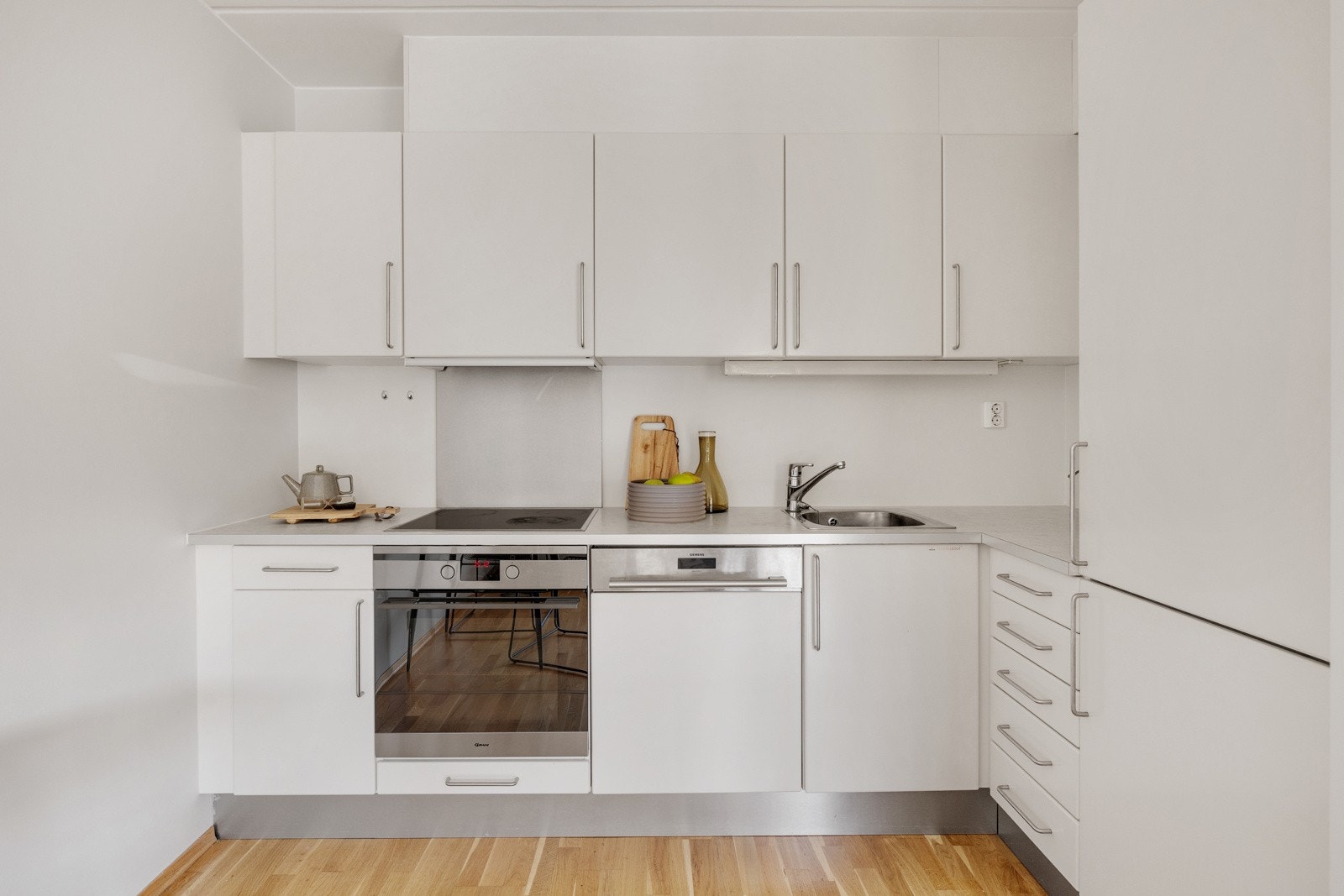 Sigdal kjøkkeninnredning med hvite, glatte fronter og laminert benkeplate gir kjøkkenet et sømløst og rent preg. Galleribilde