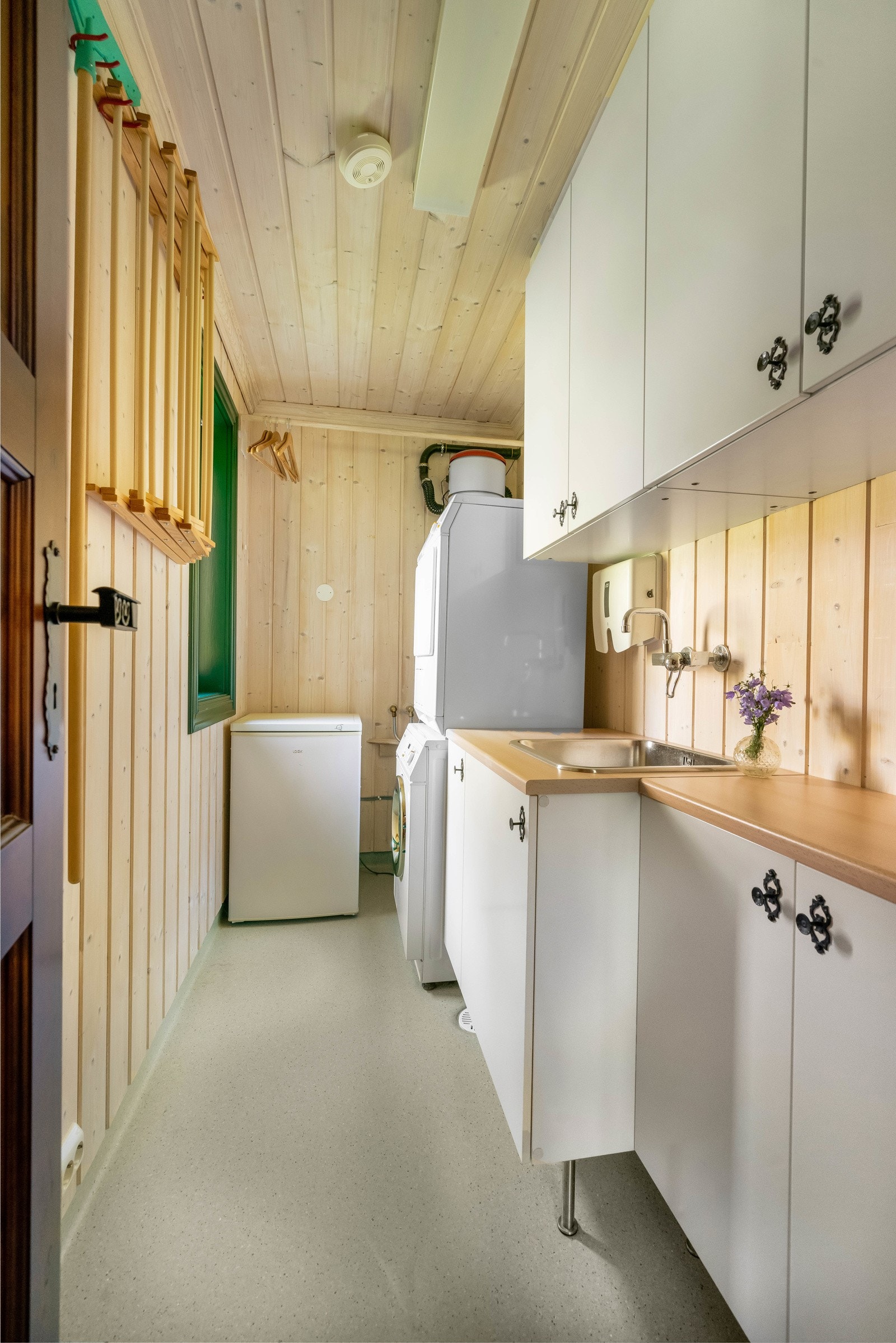 Praktisk, separat vaskerom med belegg på gulv, varmekabler og lysnet panel på vegger og i himling. Innredning med hvite slette fronter og benkeplate i laminat med nedfelt skyllekum i stål. Veggmontert ett-greps blandebatteri. Galleribilde