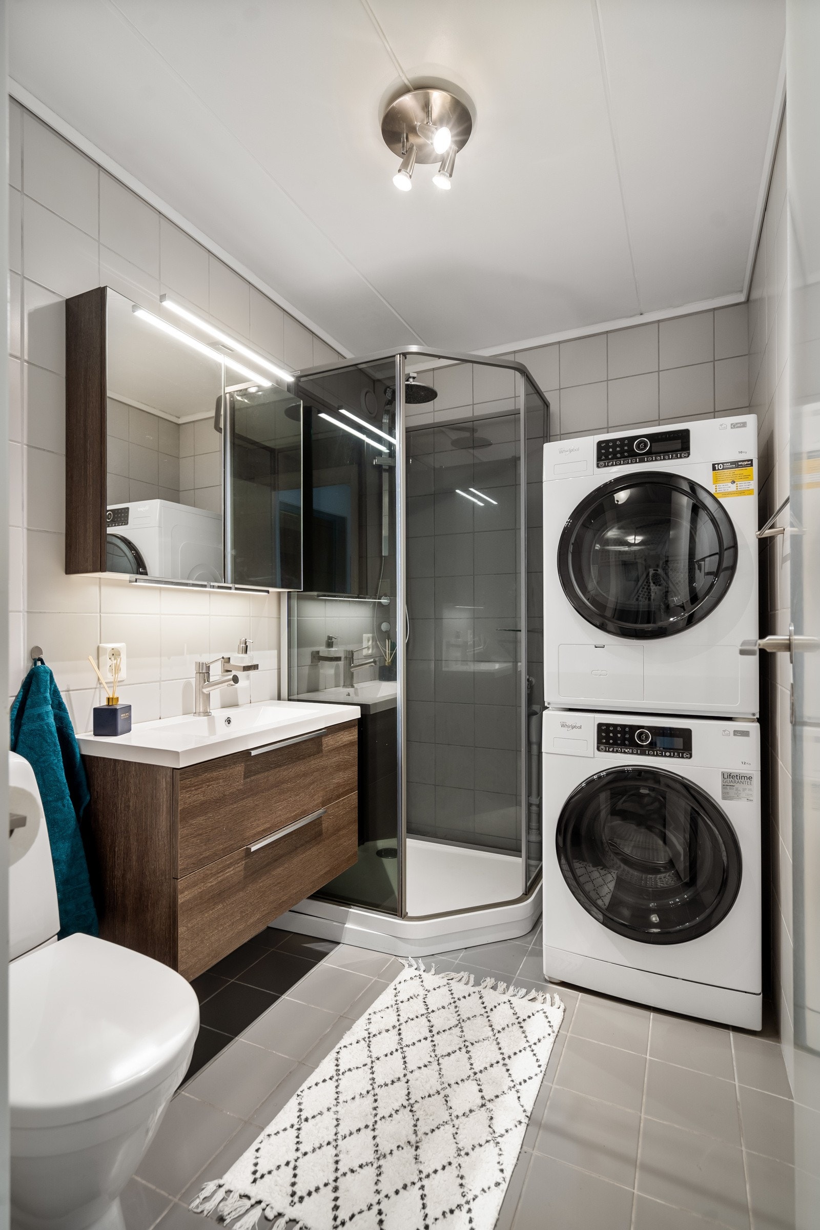 Badet er et lekkert rom flislagt i delikate farger, og med varmekabler i gulv. Rommet inneholder dusjkabinett, wc, speilskap med overhengende lys og lys i underkant, ett-greps blandebatteri, servant i innredning og plass til vaskemaskin og tørketrommel Galleribilde