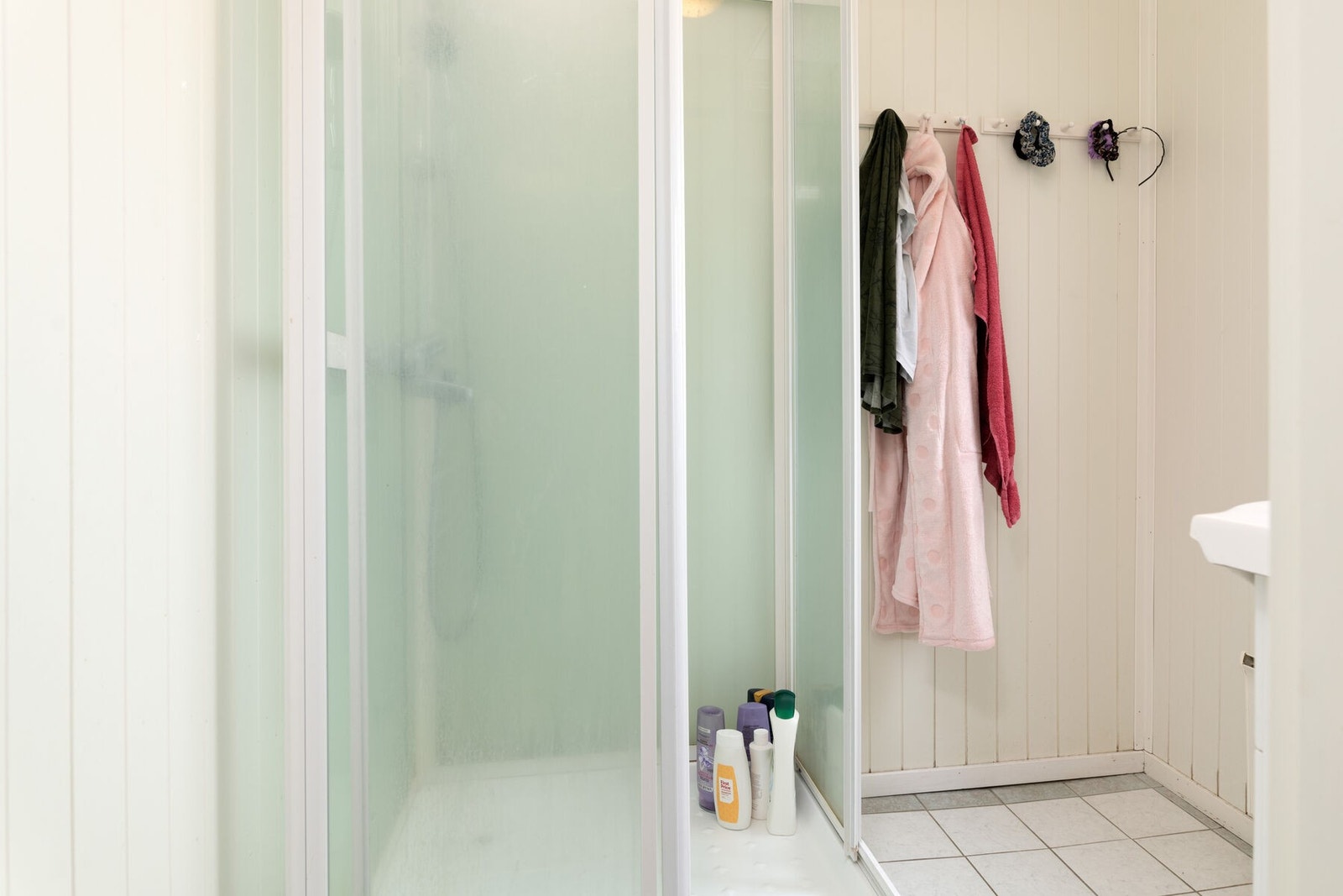 Badet har fliser på gulvet og er utstyrt med dusjkabinett og servant. Galleribilde