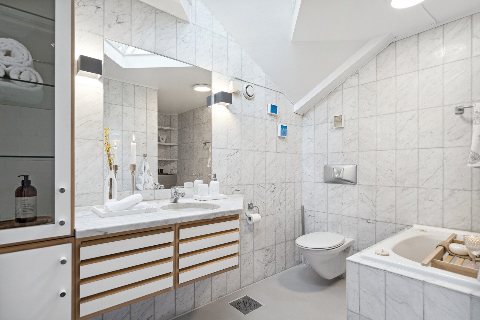 Badet er 5,5 kvm. Flislagt i marmor og med naturlig overlys via stort takvindu. Galleribilde