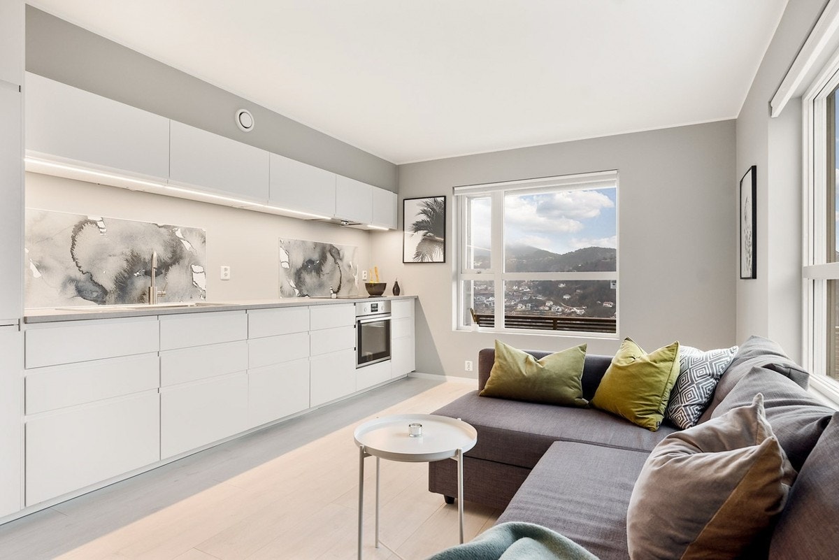 Den åpne stue- og kjøkken løsningen måles til 18,8 kvm. Kjøkkenet har hvite, slette fronter og benkeplate av lamiant. Hvitevarere er integrerte. Galleribilde