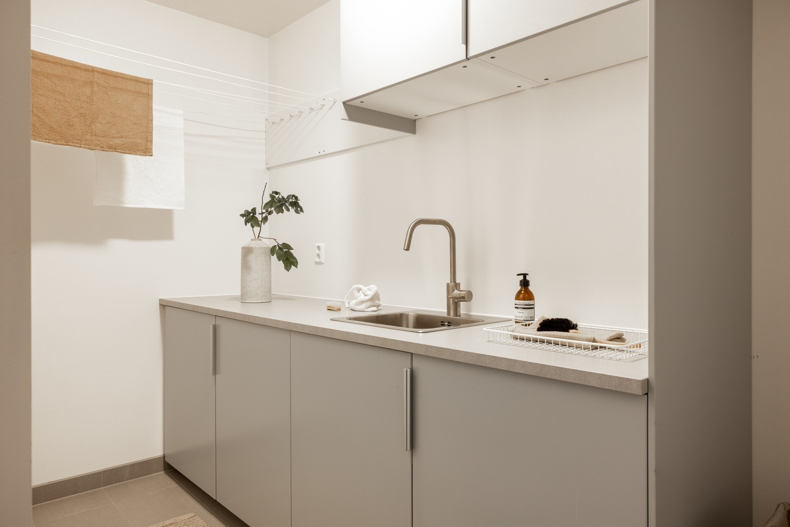 Praktisk vaskerom på 5,8 kvm med fliser på gulv, samt innredning med oppbevaringsplass og arbeidsflate. Galleribilde