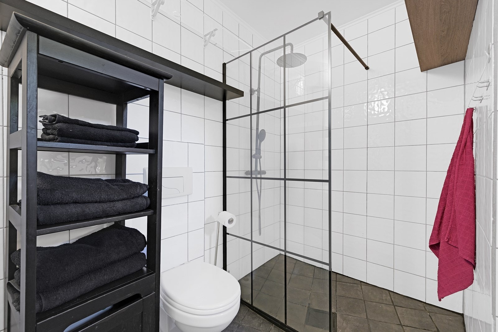 Bad/wc med varmekabler i gulv, dusjhjørne, vegghengt toalett, opplegg vaskemaskin og varmtvannstank i benk. Galleribilde