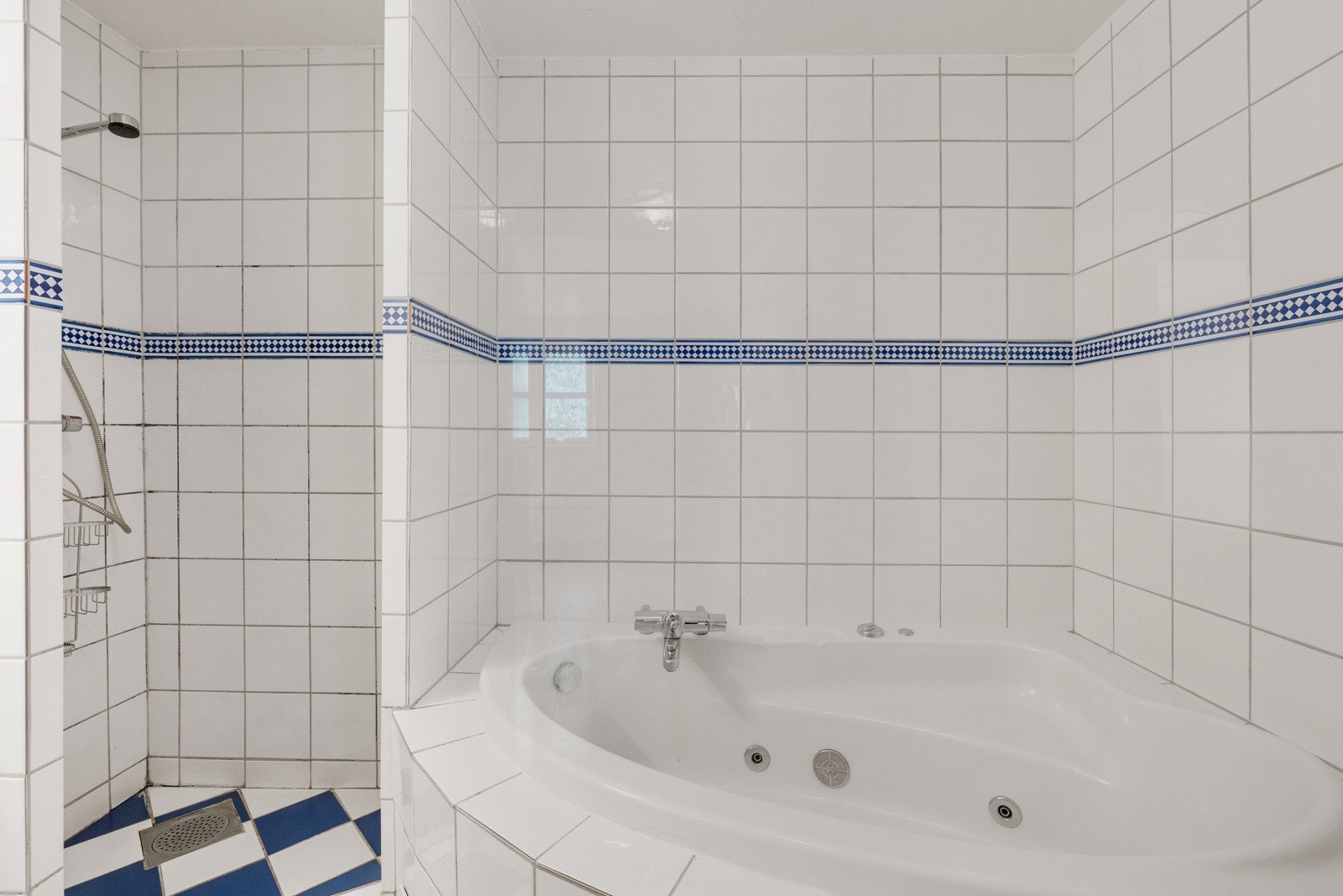 Badet inneholder servantinnredning, innmurt speil med overbelysning, gulvstående toalett, dusjnisje og innmurt badekar. Galleribilde