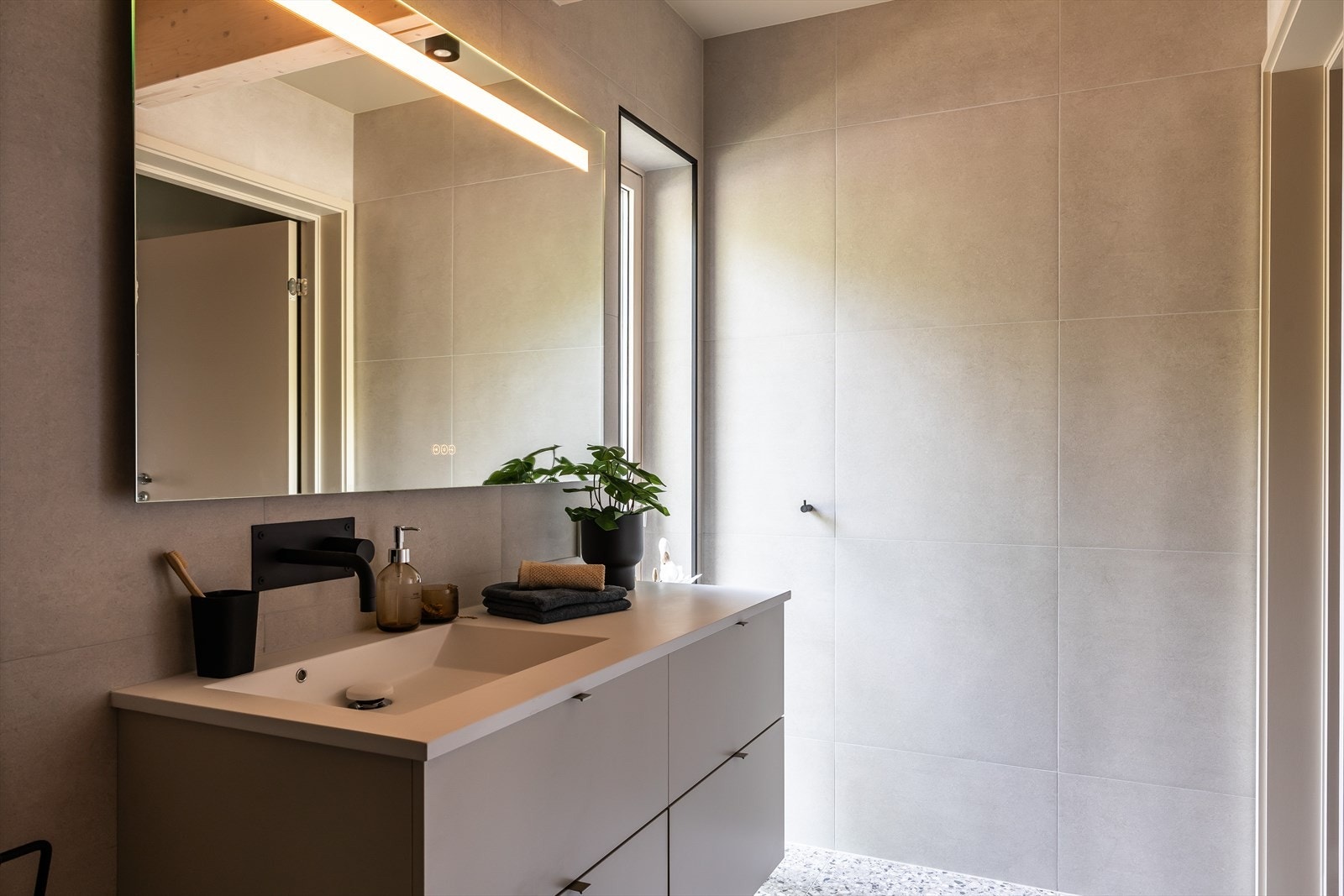 Baderom i tilknytning til hovedsoverom. Baderommet er av romslig størrelse bestående av servantskap med underskuffer, vegghengt toalett og dusjhjørne med glassvegg. Galleribilde