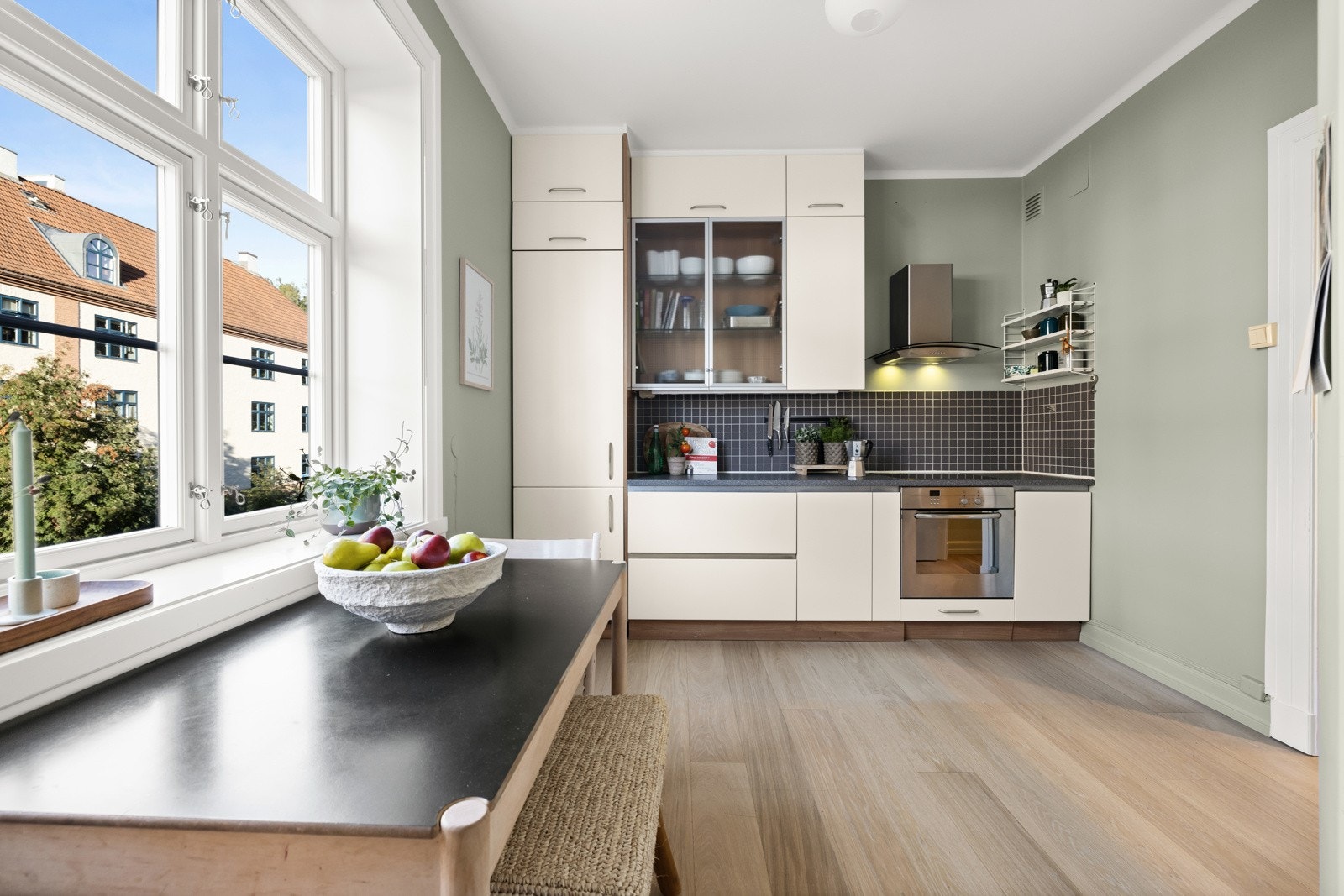 Det er plass til spisebord ved vinduet på kjøkkenet. Kjøkkenet har takhøye skap og vender mot rolig gate. Galleribilde