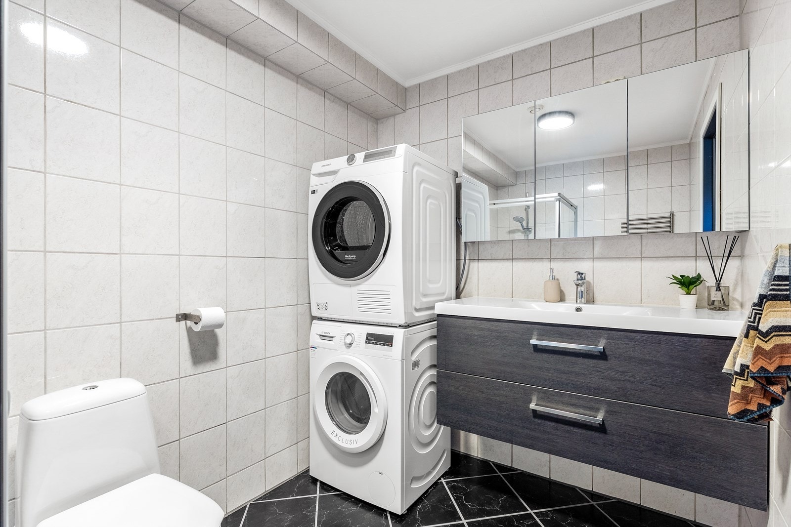 Av innredninger finnes servantinnredning med slette fronter med heldekkende servant og overliggende speilskap. Videre er det frittstående toalett, dusjhjørne med dusjgarnityr og glassdører. Galleribilde