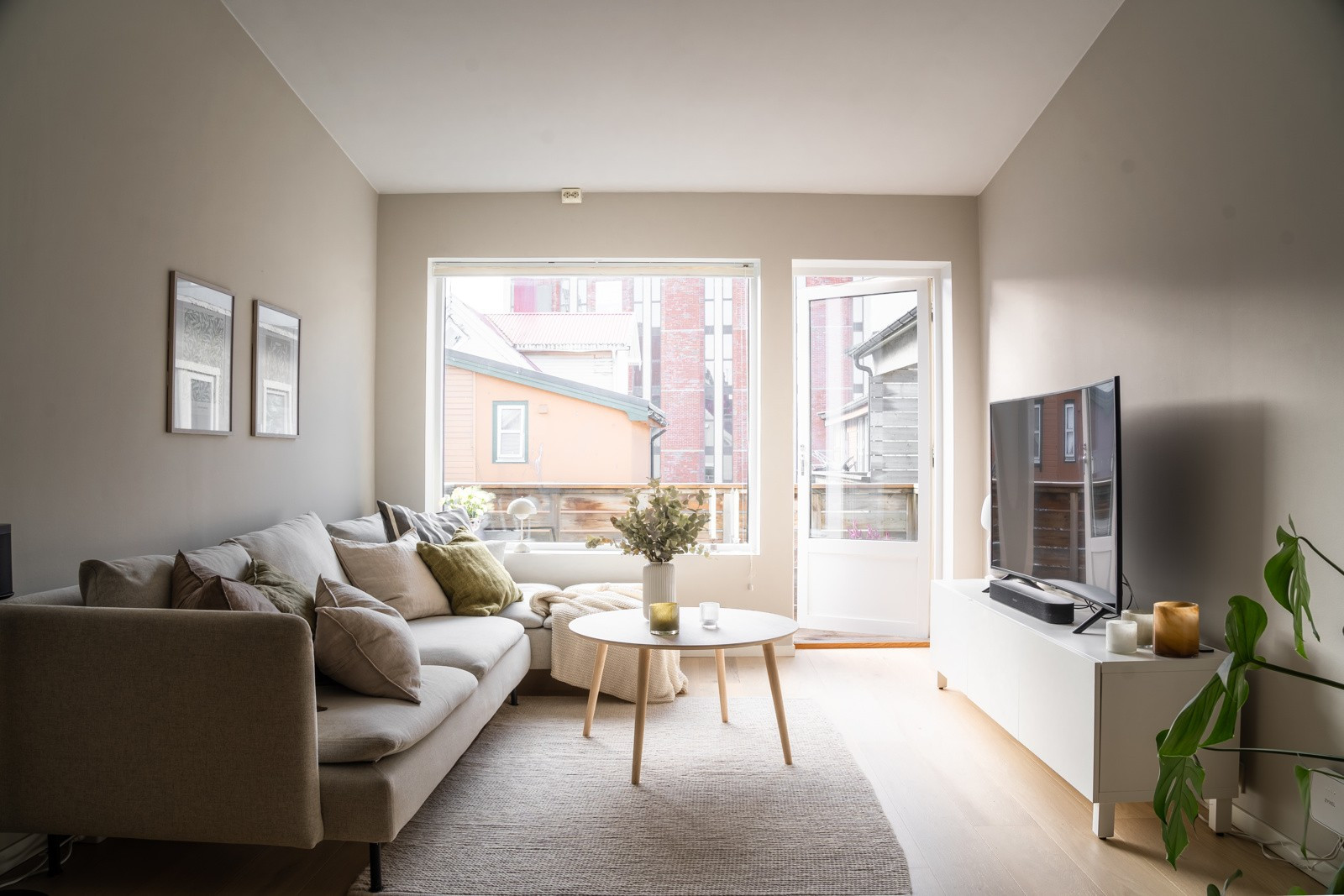 Sofagruppen har sin naturlige plass ved vinduet. Med god plass til TV på motsatt vegg. Legg merke til den generøse takhøyden og de store vindusflatene.