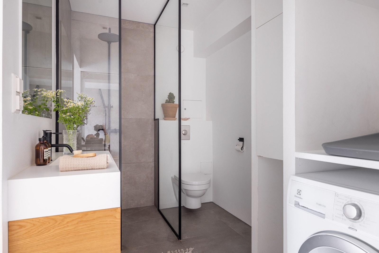 Badet i tredje etasje har opplegg for vaskemaskin, vegghengt klosett, vegghengt toalett og dusjhjørne med vegger i glass og veggmontert armatur og garnityr Galleribilde