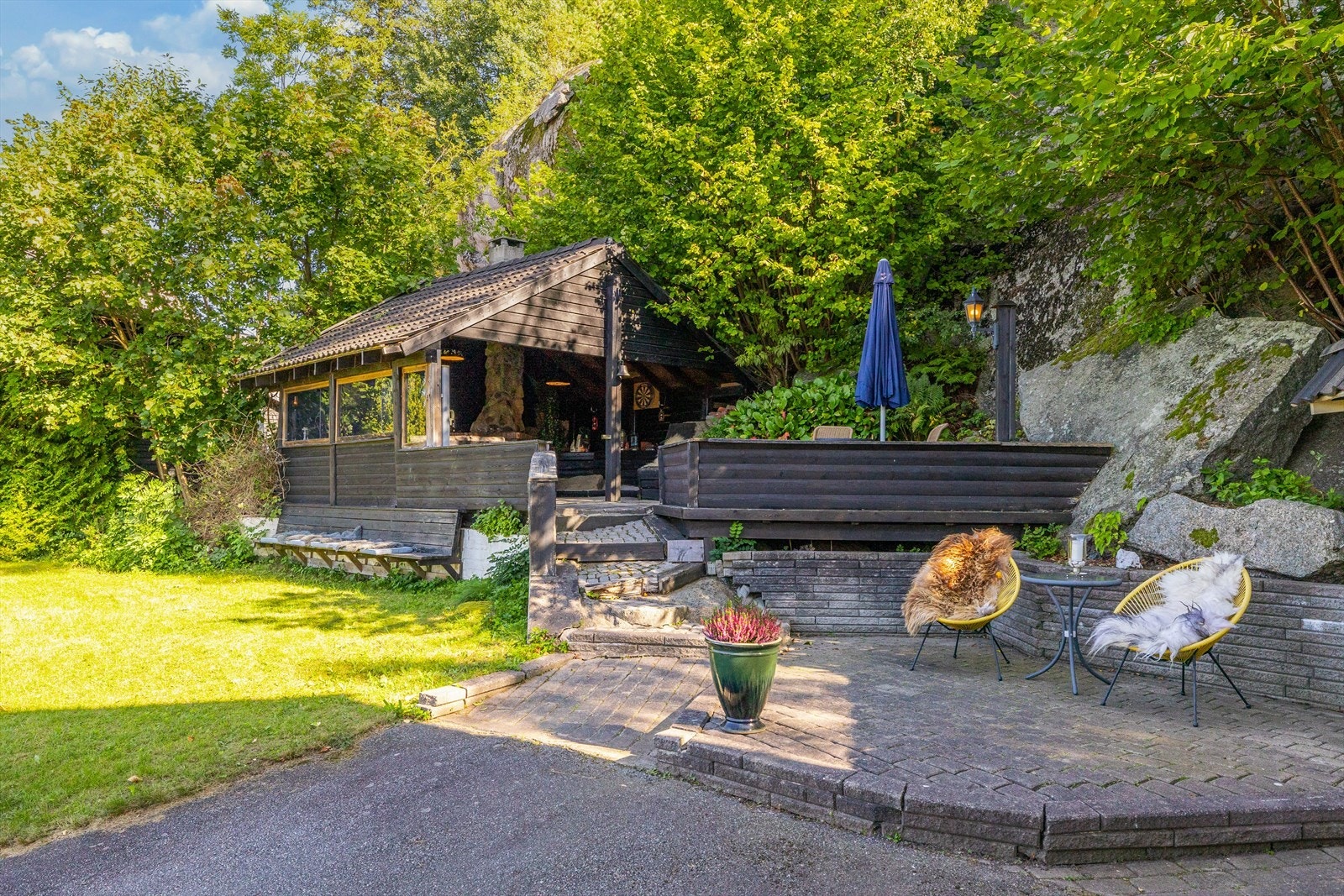 Tomten er opparbeidet med asfaltert gårdsplass, plen, busker og hekk. Det er mot gårdsplass markterrasse med belegningsstein ca 12 m2 og treplatting ca 8 m2. Galleribilde