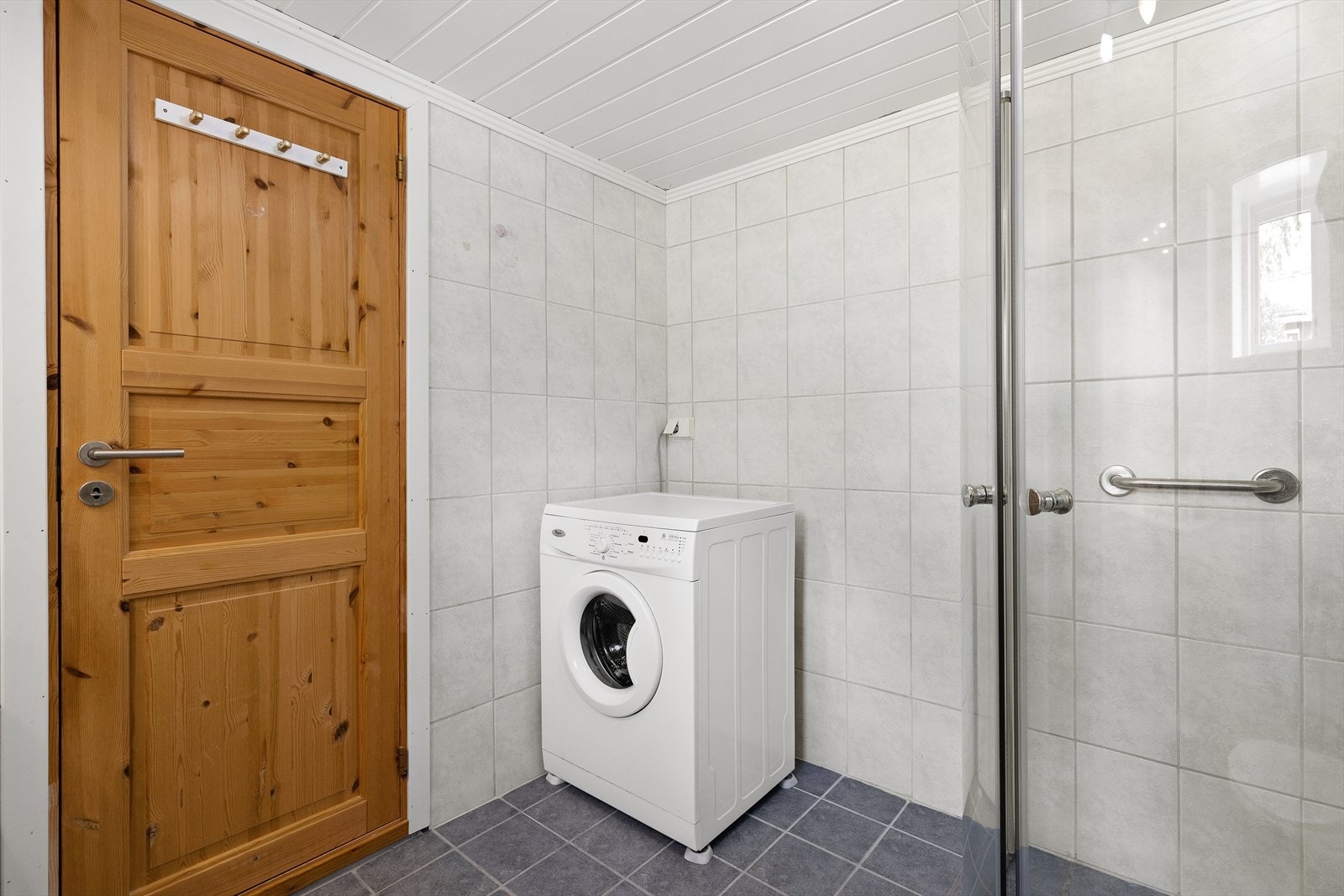 Rommet er innredet med toalett, servantinnredning med under- og overskap, speil og dusjhjørne. Det er plass og opplegg for både vaskemaskin og tørketrommel i rommet. Galleribilde