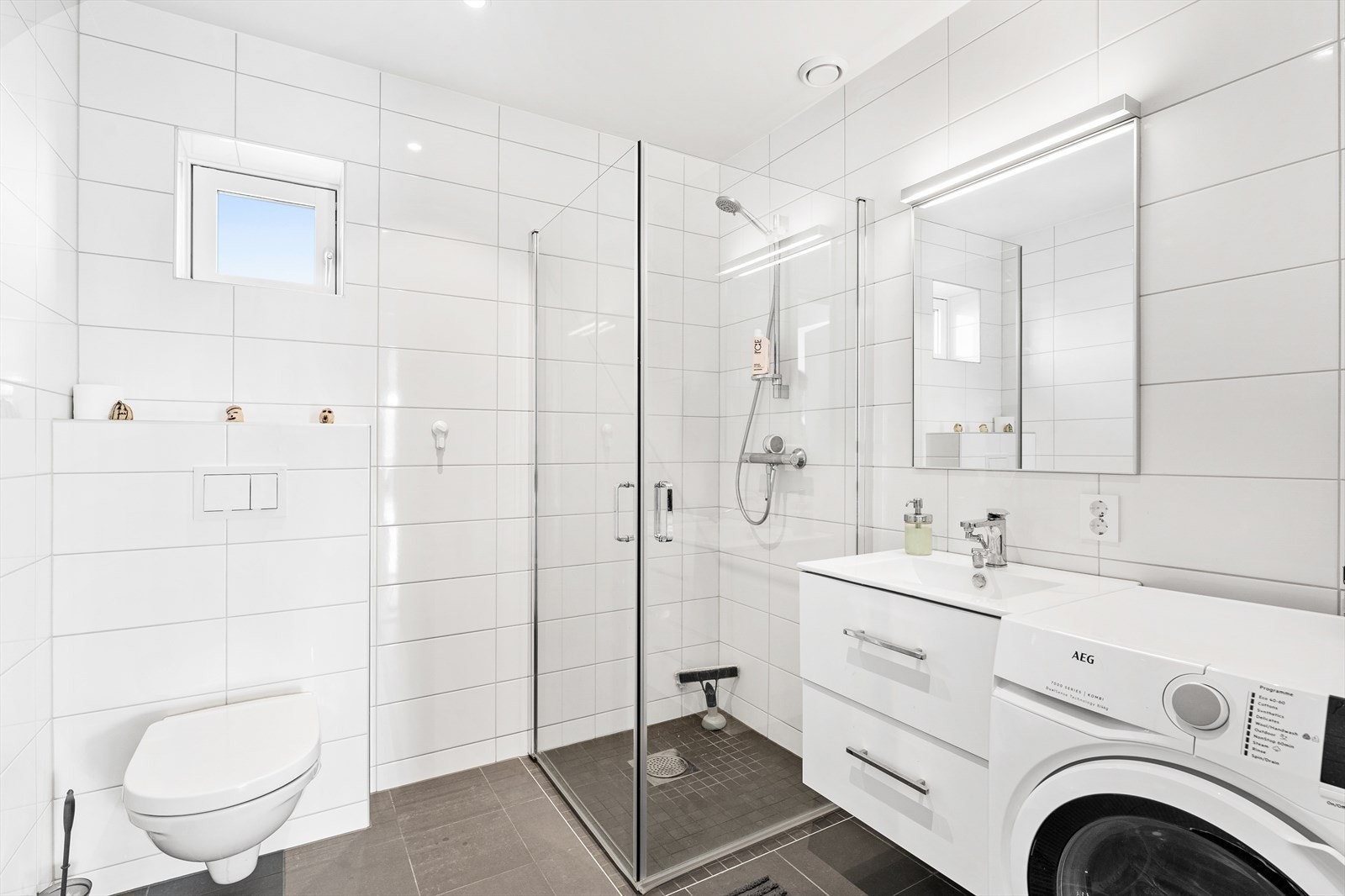 Badet er romslig og tidløst utført med lyse fliser på vegg mot mørke fliser på gulv. Galleribilde