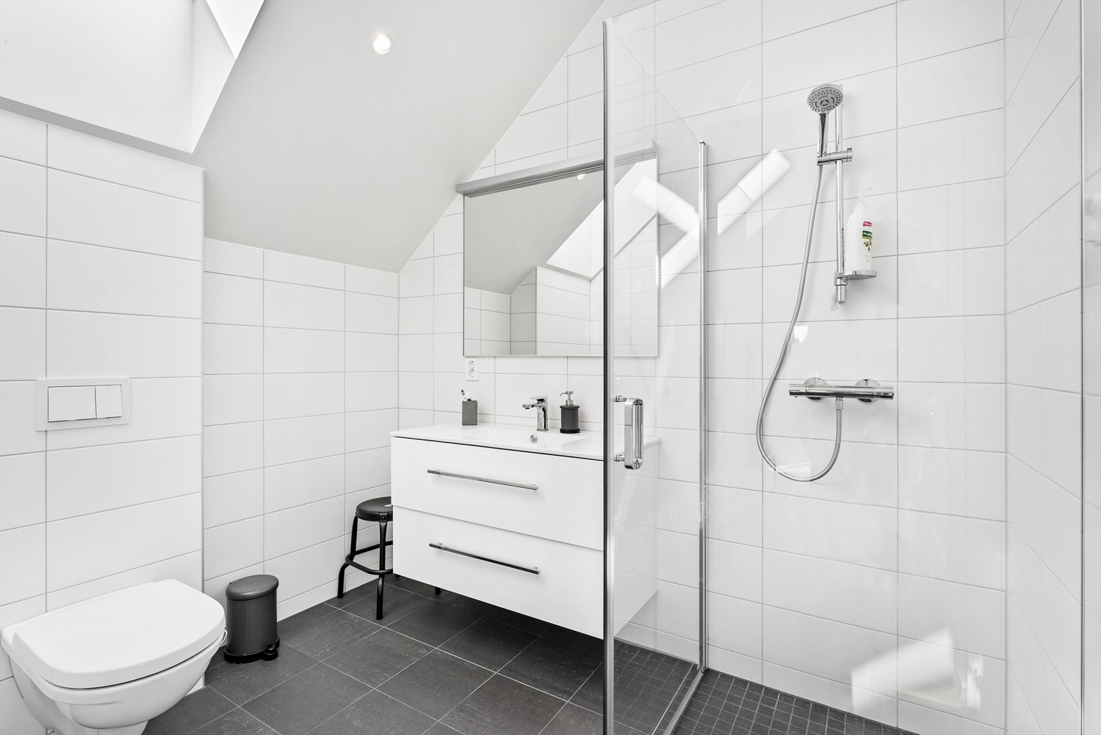 Badet er innredet med dusjhjørne med glassvegger, servant og toalett. Galleribilde