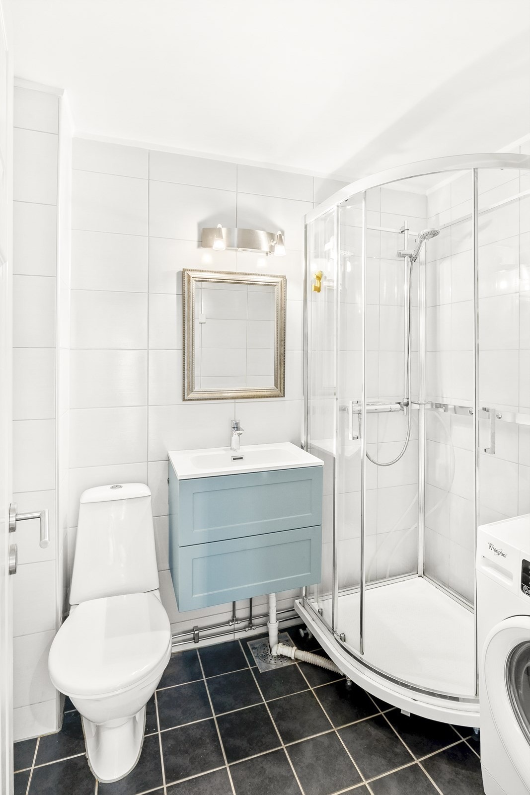 Flislagt baderom med gulvvarme. Innredningen er bestående av servant med skuffeseksjon, speil, gulvmontert klosett og opplegg for vaskemaskin. Galleribilde