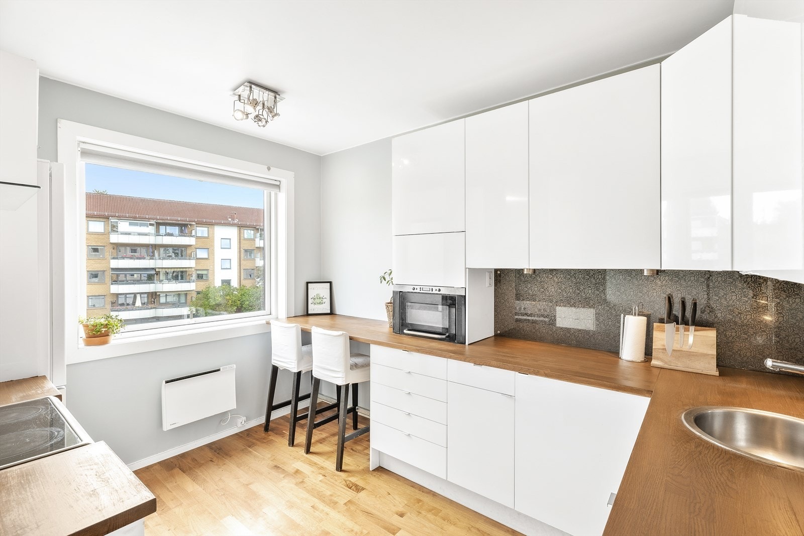 IKEA kjøkkeninnredning med slette høyglans skapfronter, heltre benkeplate med sprutplate på bakvegg og enkel oppvaskkum. Galleribilde