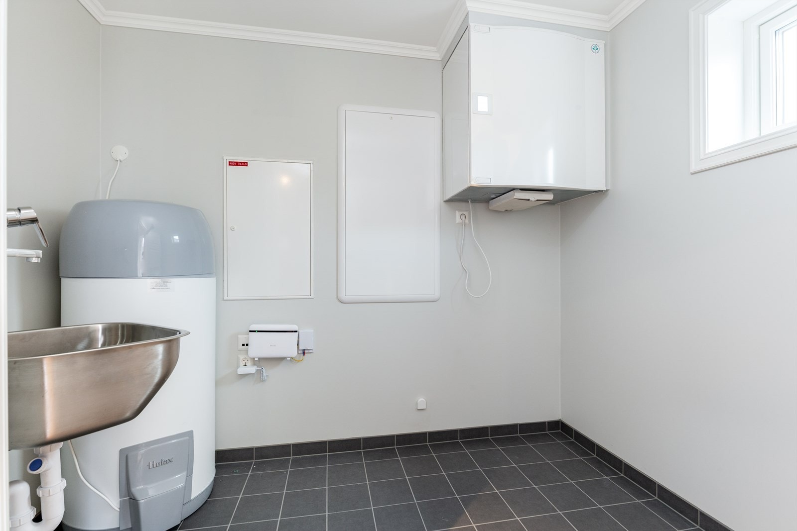 Vaskerom med utslagsvask og flislagt gulv som ligger praktisk til ved gangen i 1. etasje. Her er varmtvannsbereder og øvrige tekniske installasjoner plassert. Galleribilde