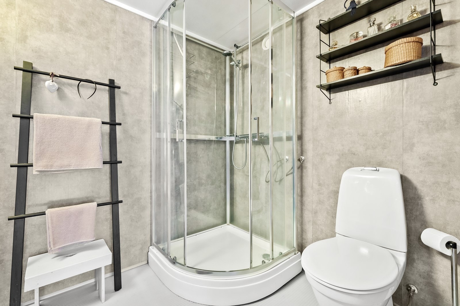 Badet har dusjkabinett og fliser på betong. Galleribilde