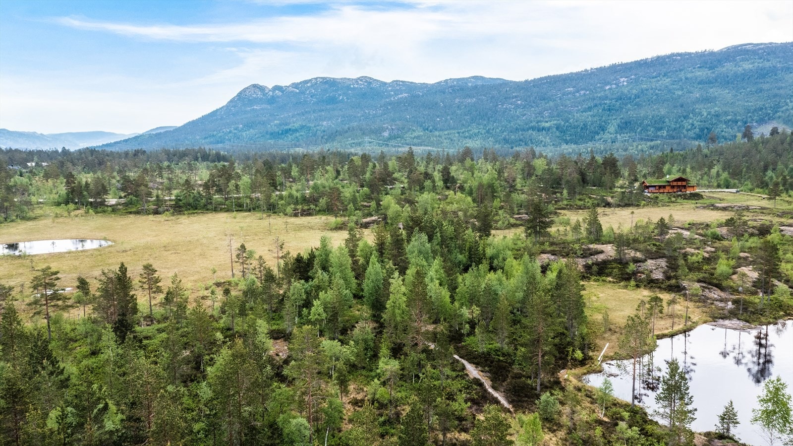 Tomten ligger solrikt til i flatt terreng med utsikt mot fjellene og landskapet rundt, samt vannspeilet i Nystulvannet Galleribilde