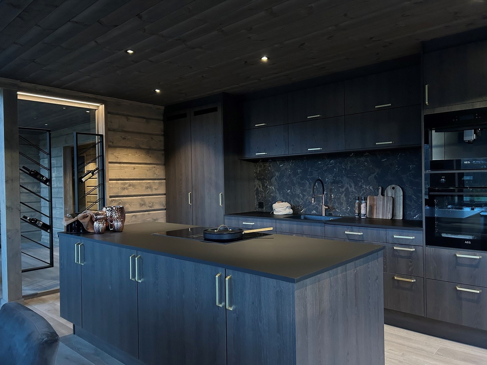 Glassfelt mellom vegg og søyle og inn mot kjøkken med vinstativ. Galleribilde