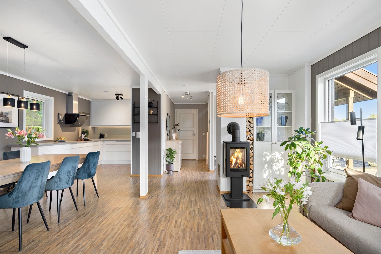 Stue og kjøkken ligger i åpen løsning, med gjennomgående dagslys, laminatgulv og overflater som ble malt i 2023. Galleribilde