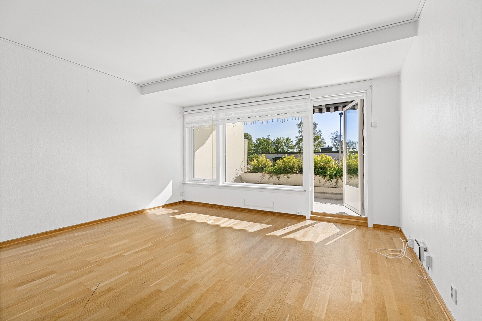 Ut mot terrassen er det to store vinduer og en glassdør som sørger for herlig dagslys Galleribilde