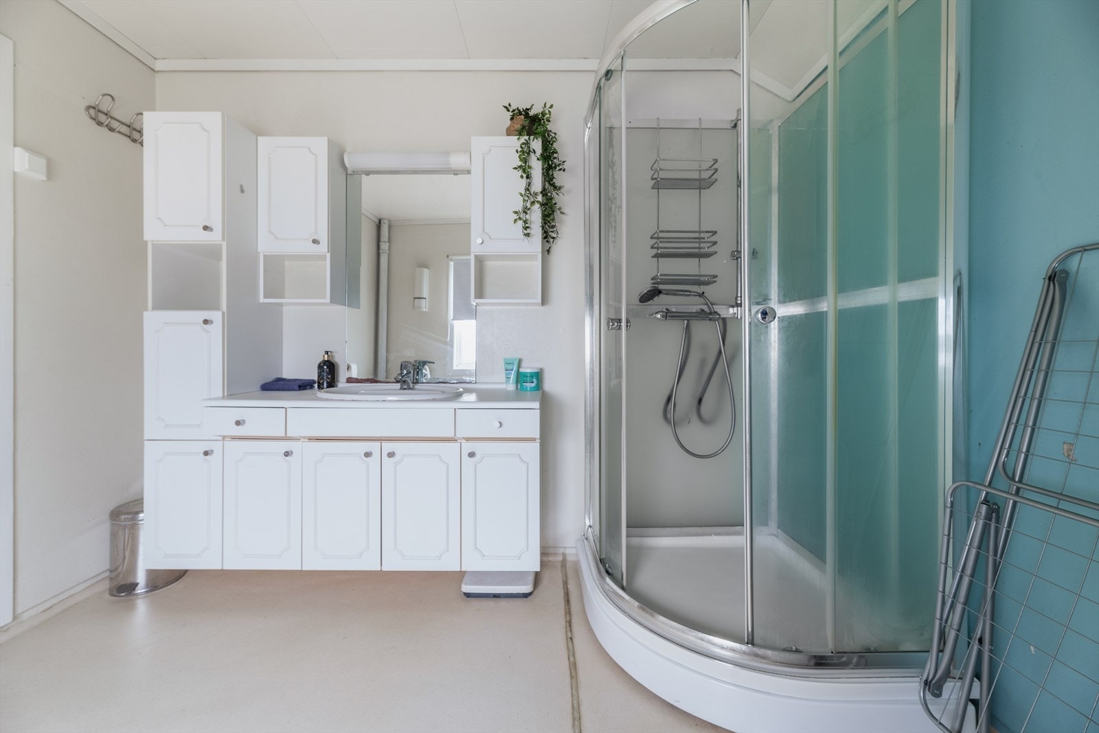 Det er en romslig innredning med god skapplass, hvor det er hvite, profilerte fronter. Nedfelt servant med speilflate og belysning over. Galleribilde