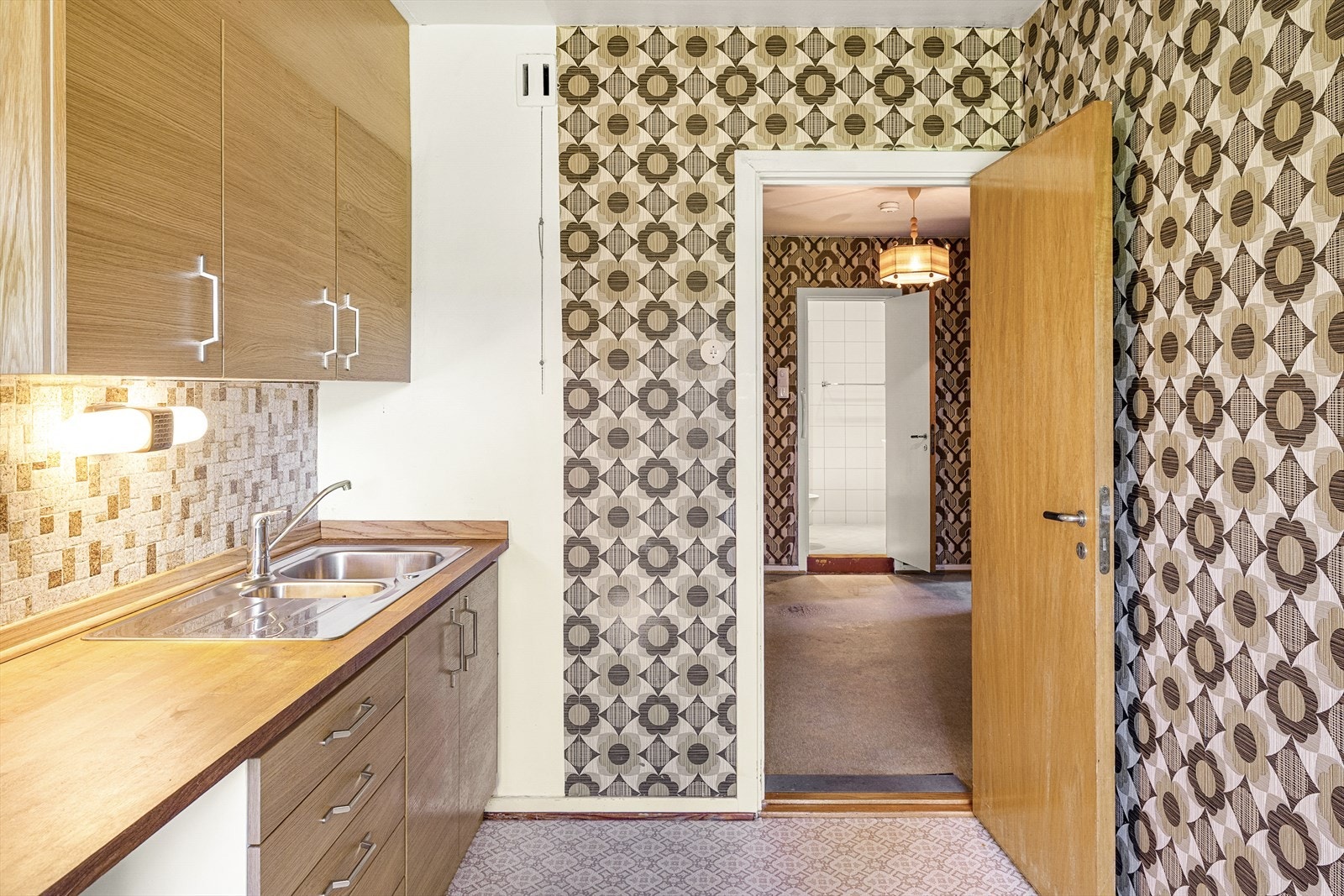 Kjøkkeninnredning med malt originalt høyskap, ellers kjøkkeninnredning med slette finerte eikefronter, heltre benkeplate med fliser over, oppvaskkum, ventilator og opplegg for oppvaskmaskin. Galleribilde