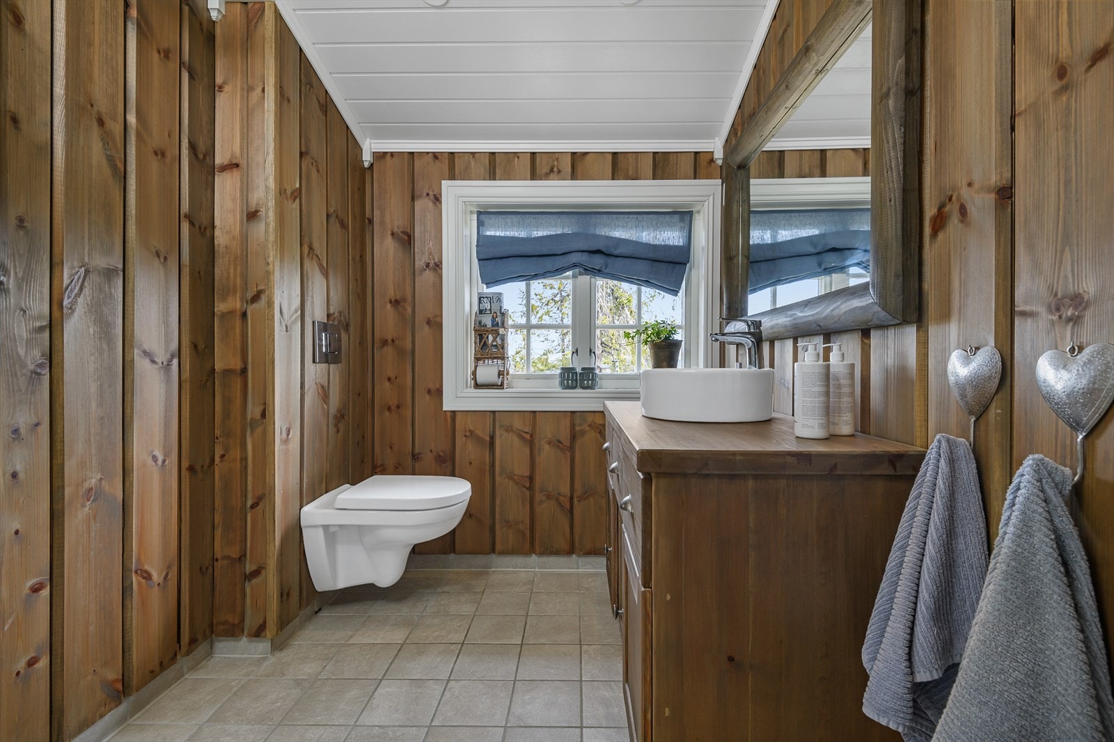 Lunt og innbydende bad/wc med flislagt gulv og panelte vegger. Galleribilde