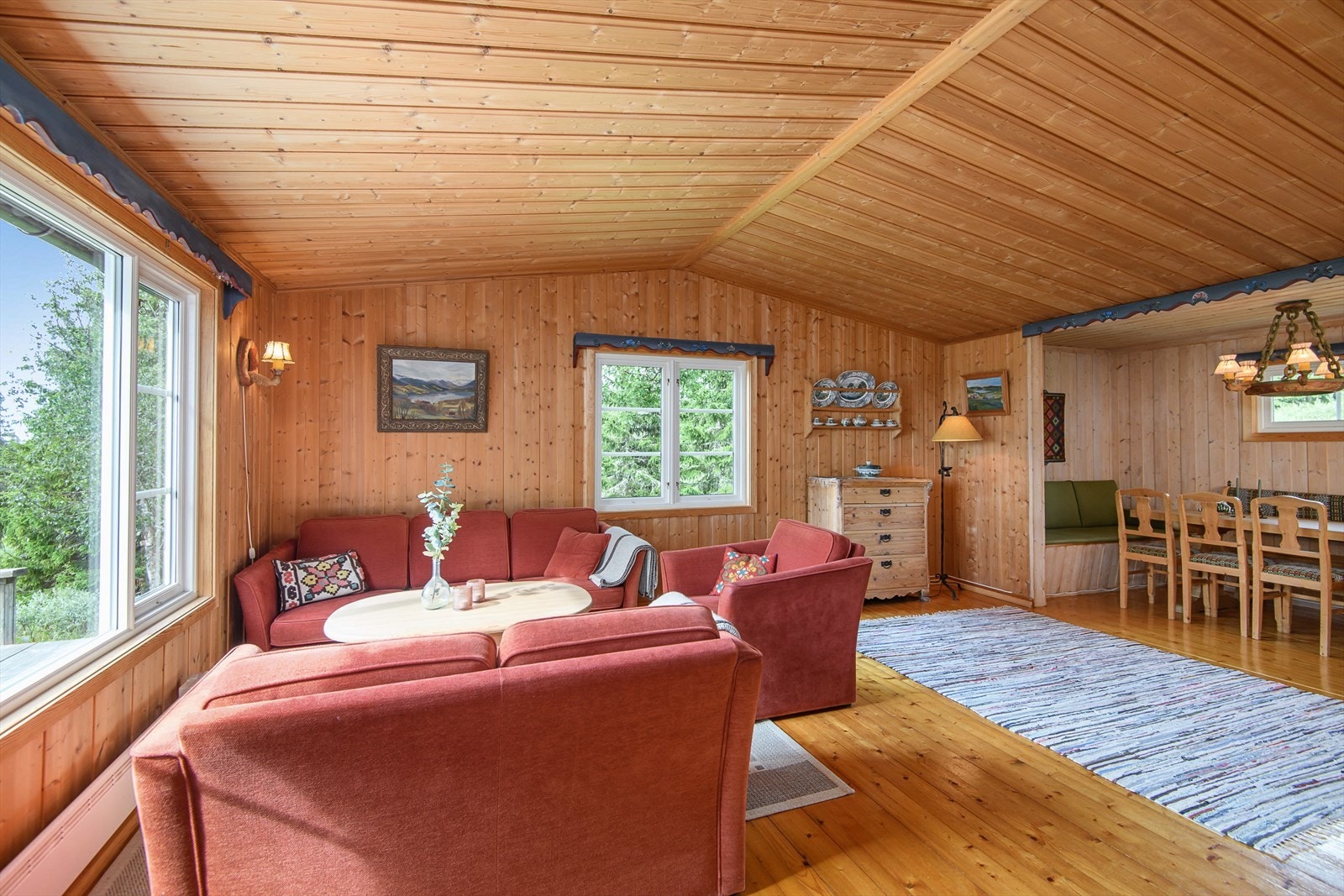 Romslig stue/spisestue med tregulv, panelte vegger og tak. Galleribilde