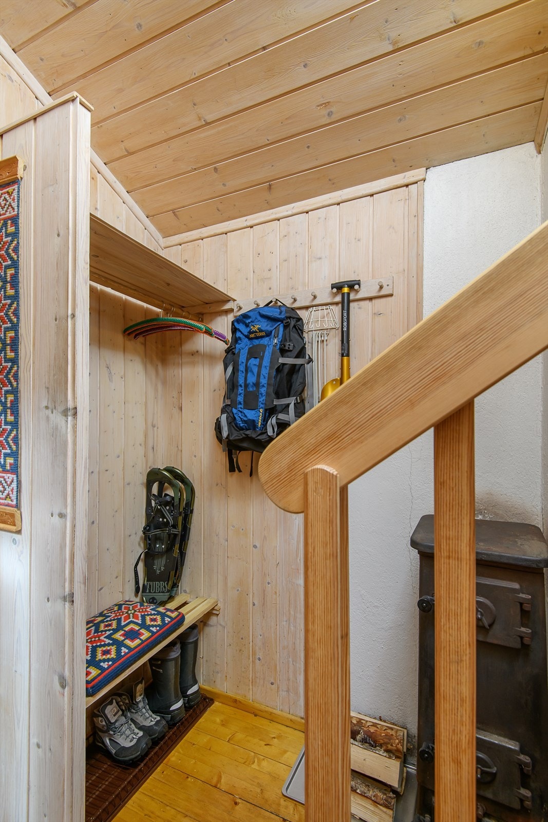 Bilde tatt fra vindfanget og inn i gangen. Vedovn for oppvarming. Plass til å henge fra seg yttertøy og utstyr. Galleribilde
