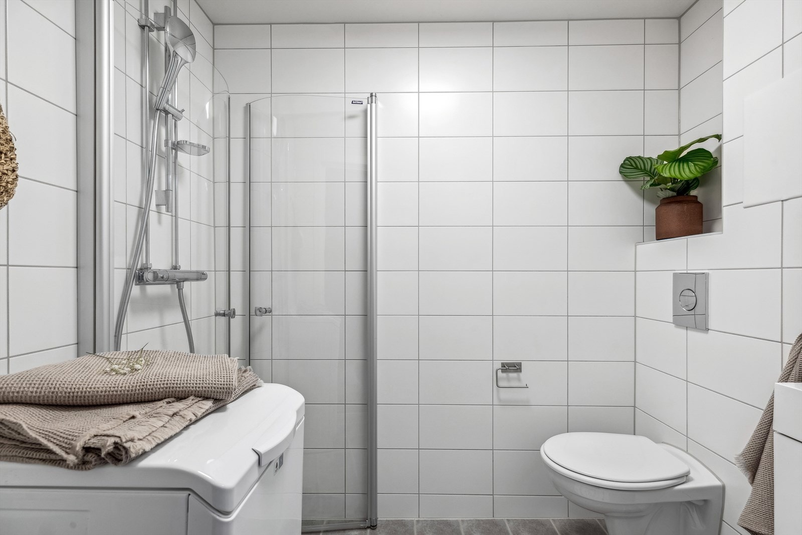 Fint baderom fra 2014. Innredning med hvite glatte fronter bestående av servantskap med heldekkende servant, overskap med speildører, vegghengt wc og dusjhjørne med svingdører. Galleribilde