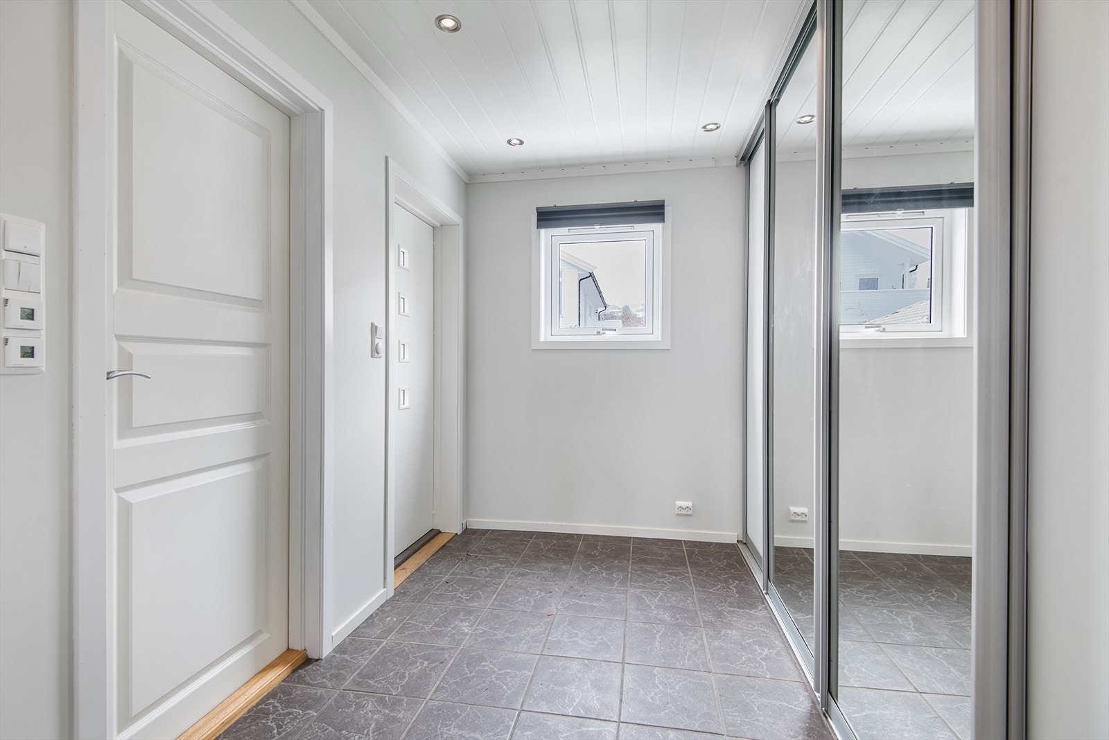 Den flislagte entrèen har skyvedørsgarderobe med speildører. Ved siden av inngangsdøren finner vi et praktisk bad/ vaskerom. Galleribilde