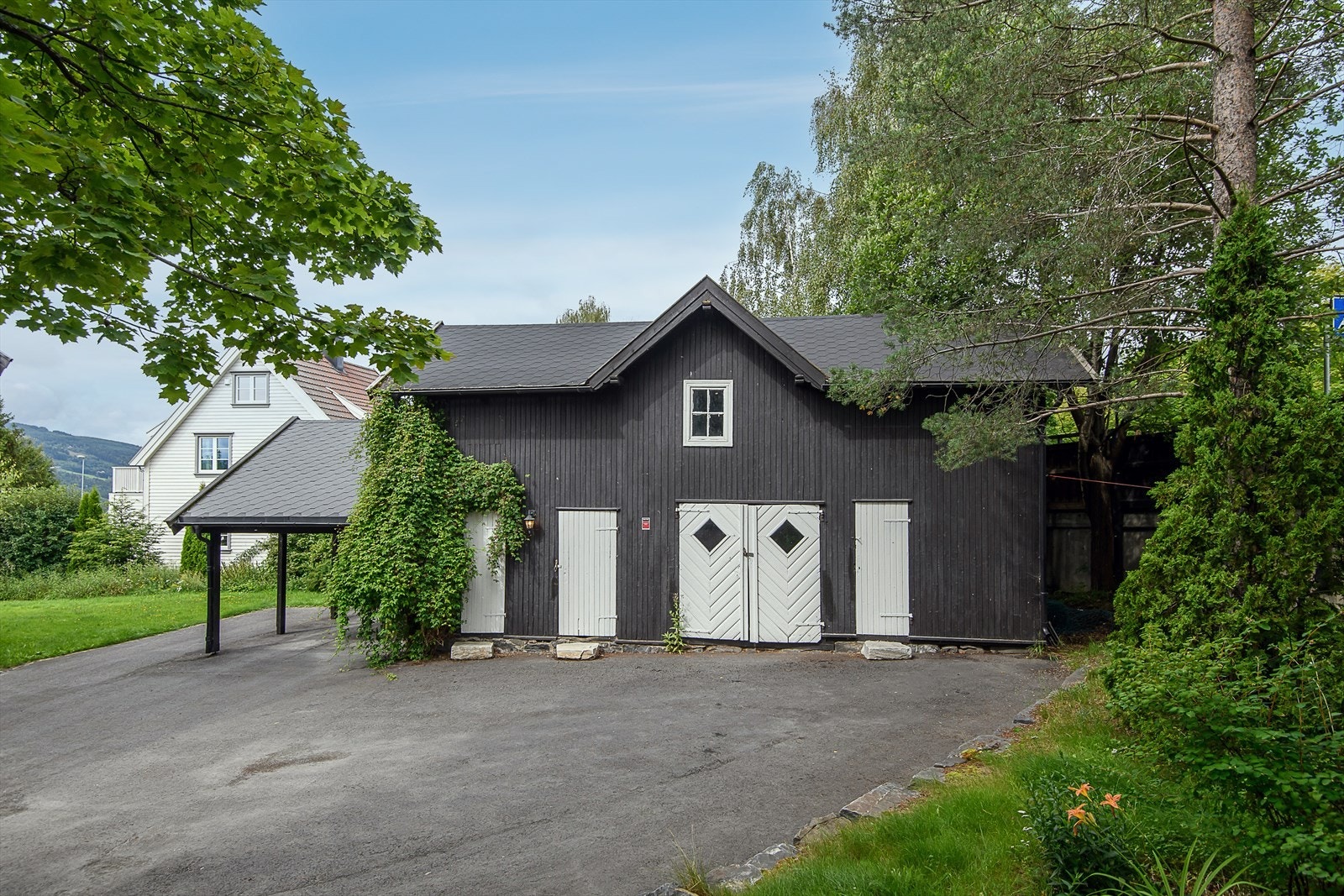 Romslig uthus i enkel standard. Carport i enden av uthuset. Galleribilde