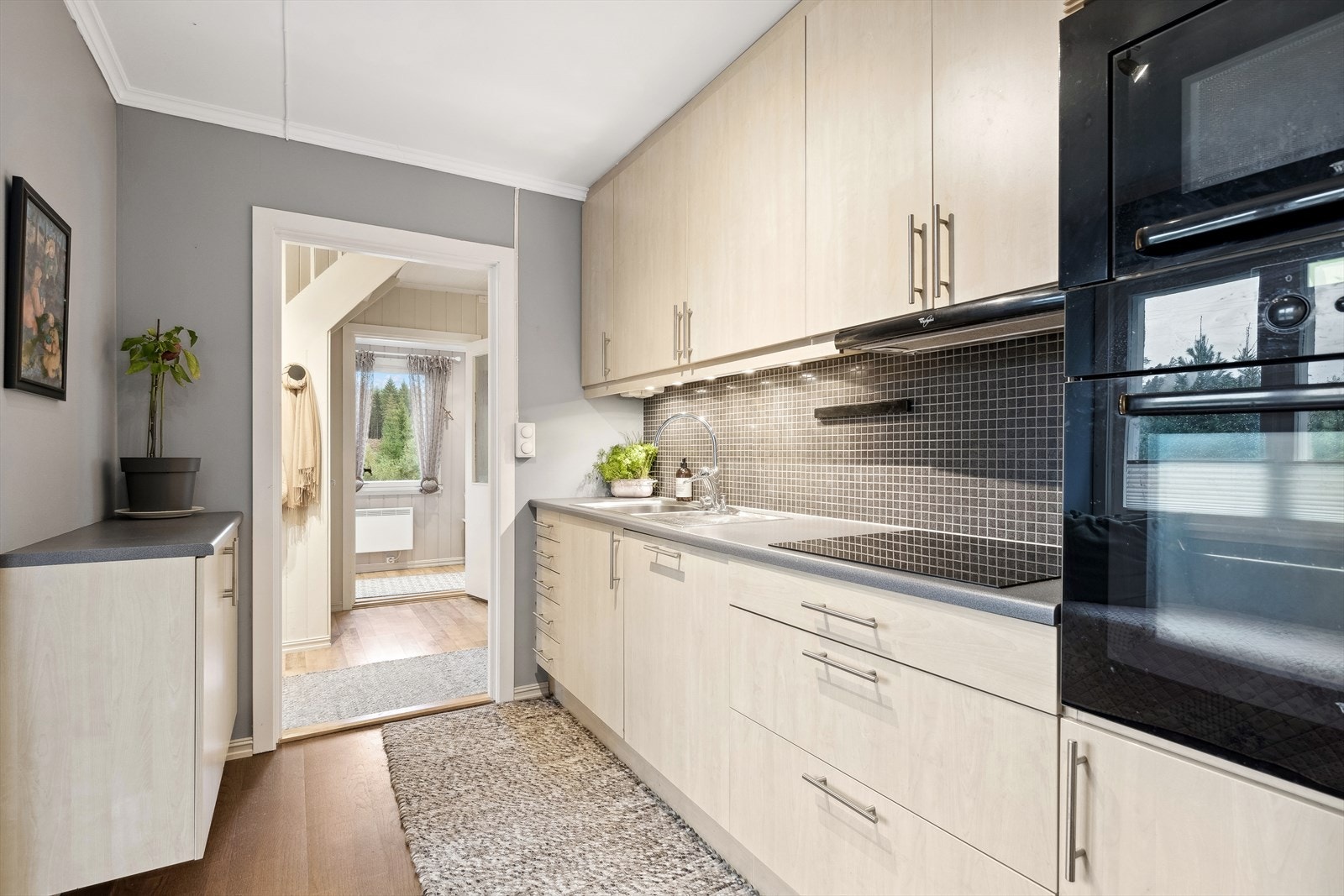 Sigdal kjøkkeninnredning med slette finérlaminerte fronter med aluminiumshåndtak, plastlaminert benkeplate med avrundet vaskekum i børstet stål og ettgreps blandebatteri i rustfritt stål. Galleribilde