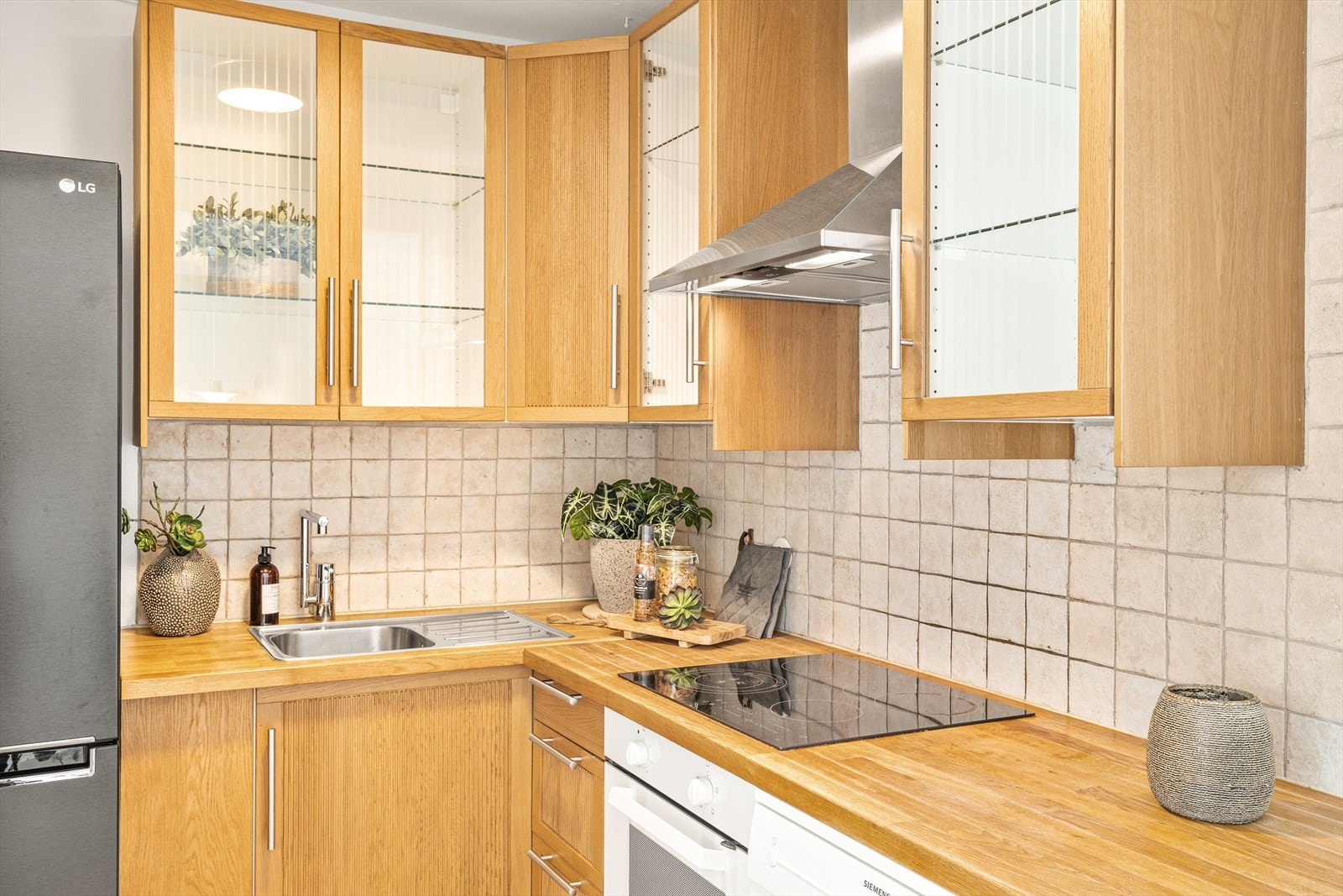 Kjøkkeninnredning med profilerte eikefronter, heltre eik benkeplate med fliser over, oppvaskkum, ventilator, opplegg for oppvaskmaskin og integrerte hvitevarer som stekeovn og koketopp. Kjøl-/fryseskap fra 2021 og oppvaskmaskin følger ved salg. Galleribilde