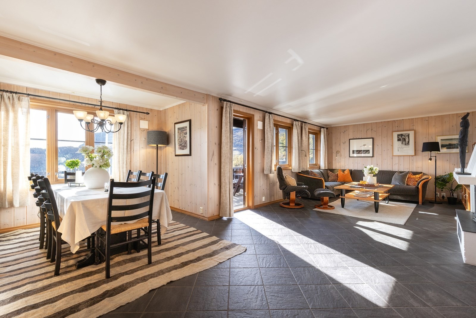Romslig stue med store vindusflater, hyggelig spiseplass og utgang til veranda. Galleribilde