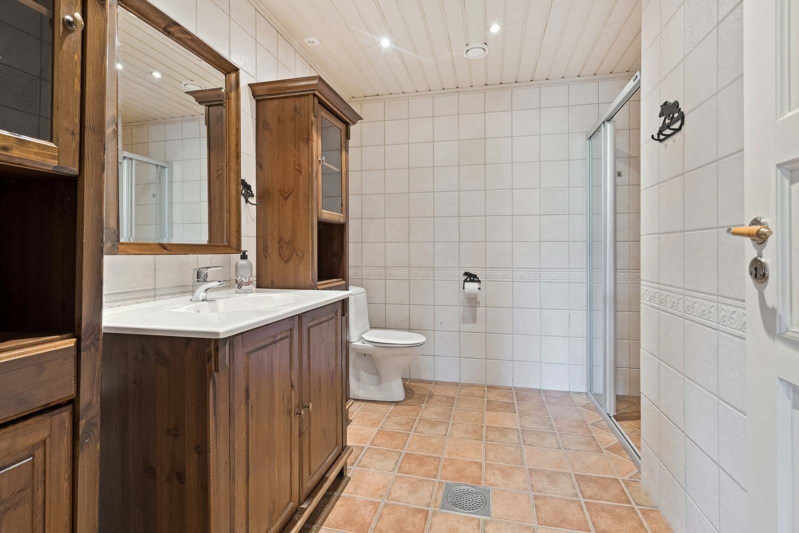 Bad i underetasje, med fliser på gulv og vegg, wc, moderne innredning, dusj. Opplegg for vaskemaskin. Galleribilde