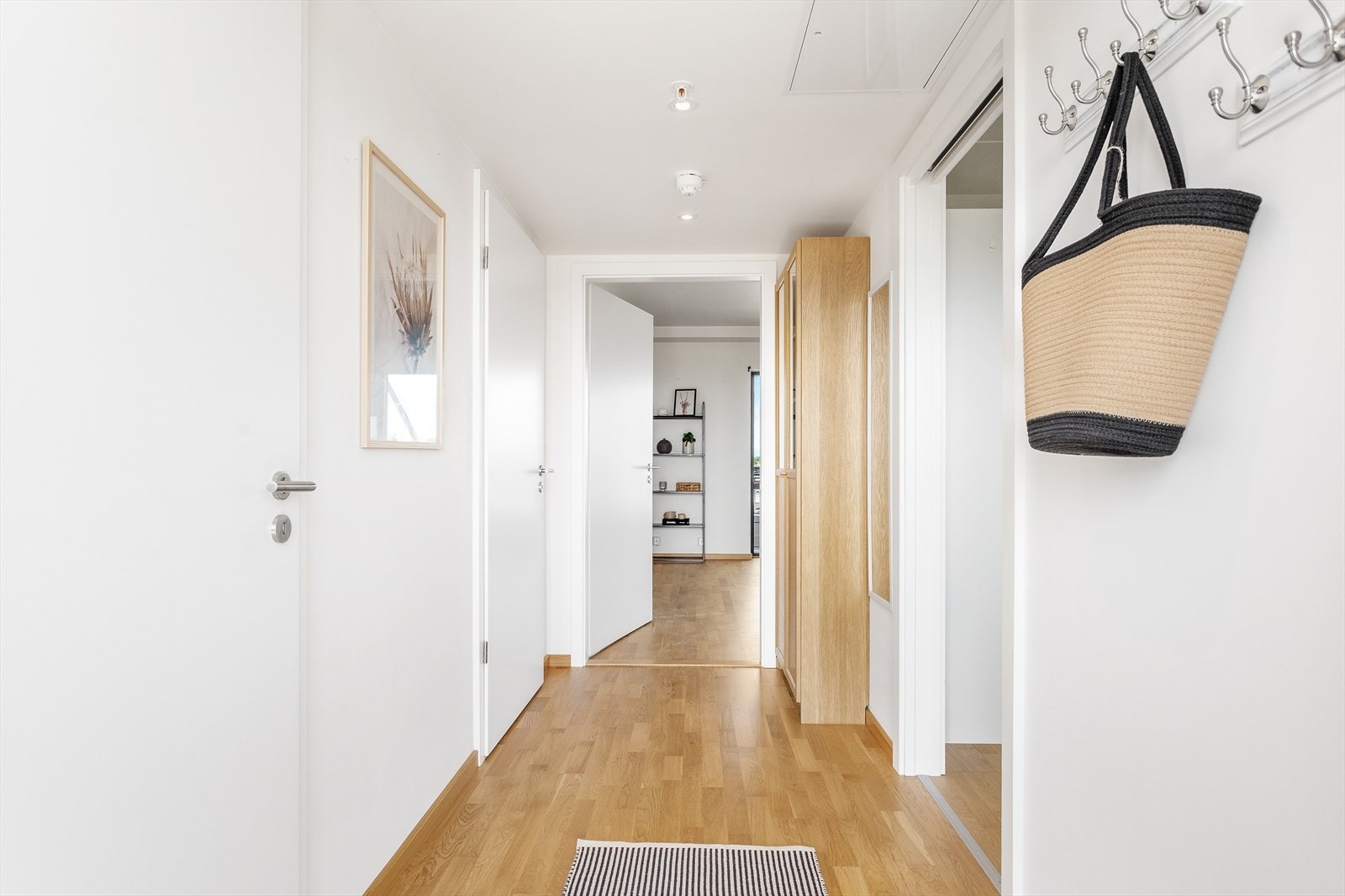 Entreen gir et representativt inntrykk av hva som venter lengre inn med hvite vegger, downlights i himling og parkett over gulv med vannbåren varme. Galleribilde