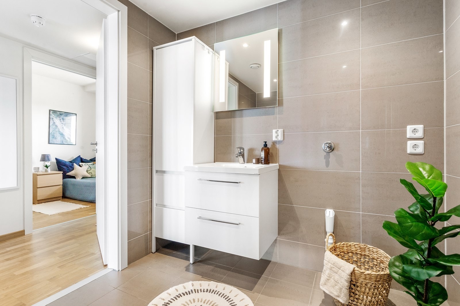 Badet ved entreen har veggmontert toalett, dusjhjørne med innfellbare glassvegger og opplegg for vaskemaskin. Galleribilde