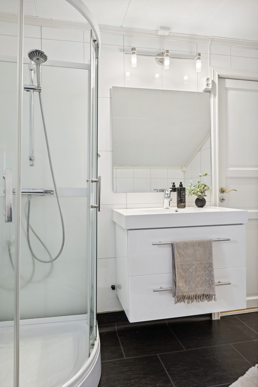 Badet er innredet med servantinnredning, speil, lys, og dusjkabinett Galleribilde