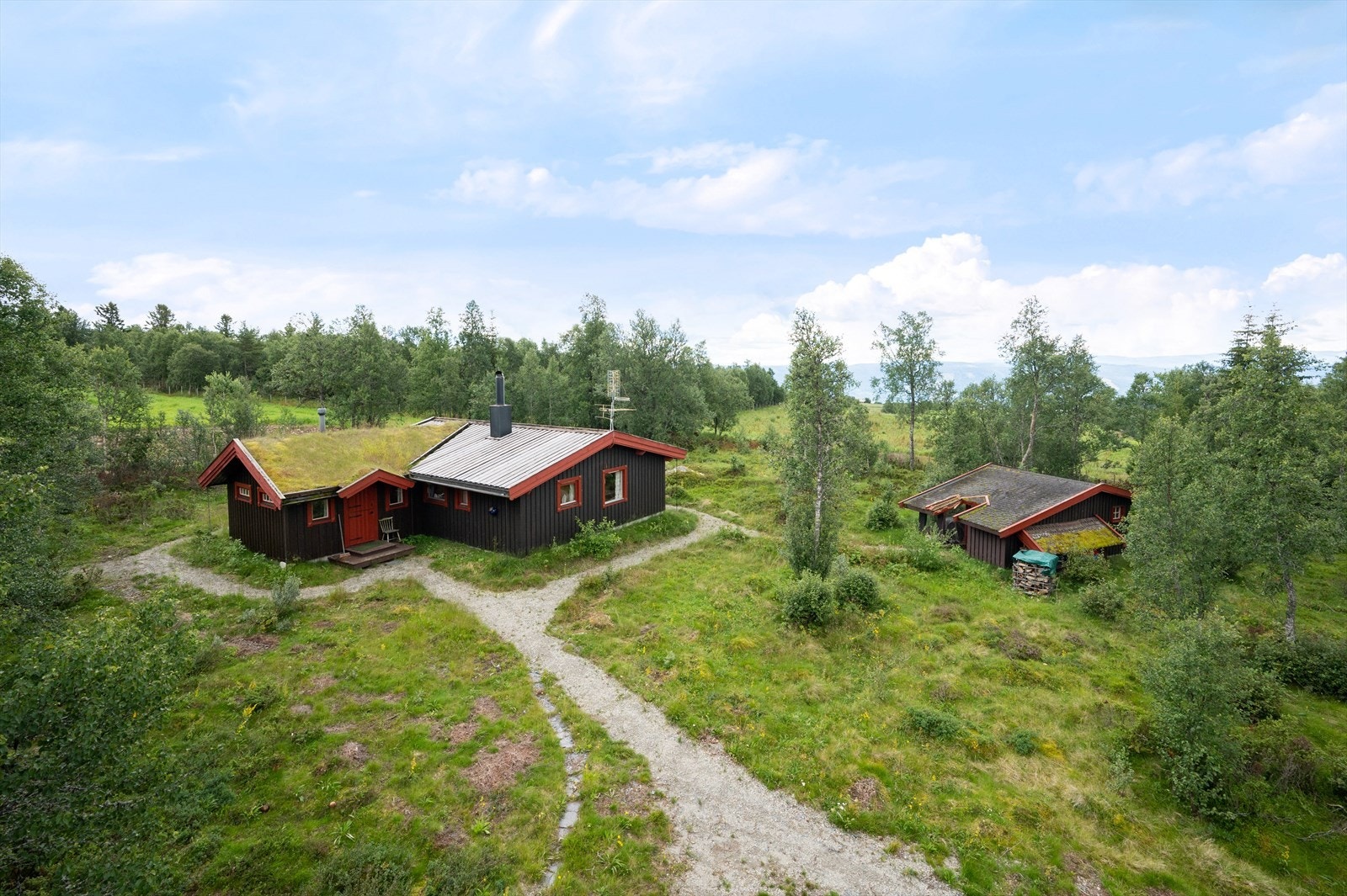 Tomten er inngjerdet og det er grusede gangstier mellom byggene. Galleribilde