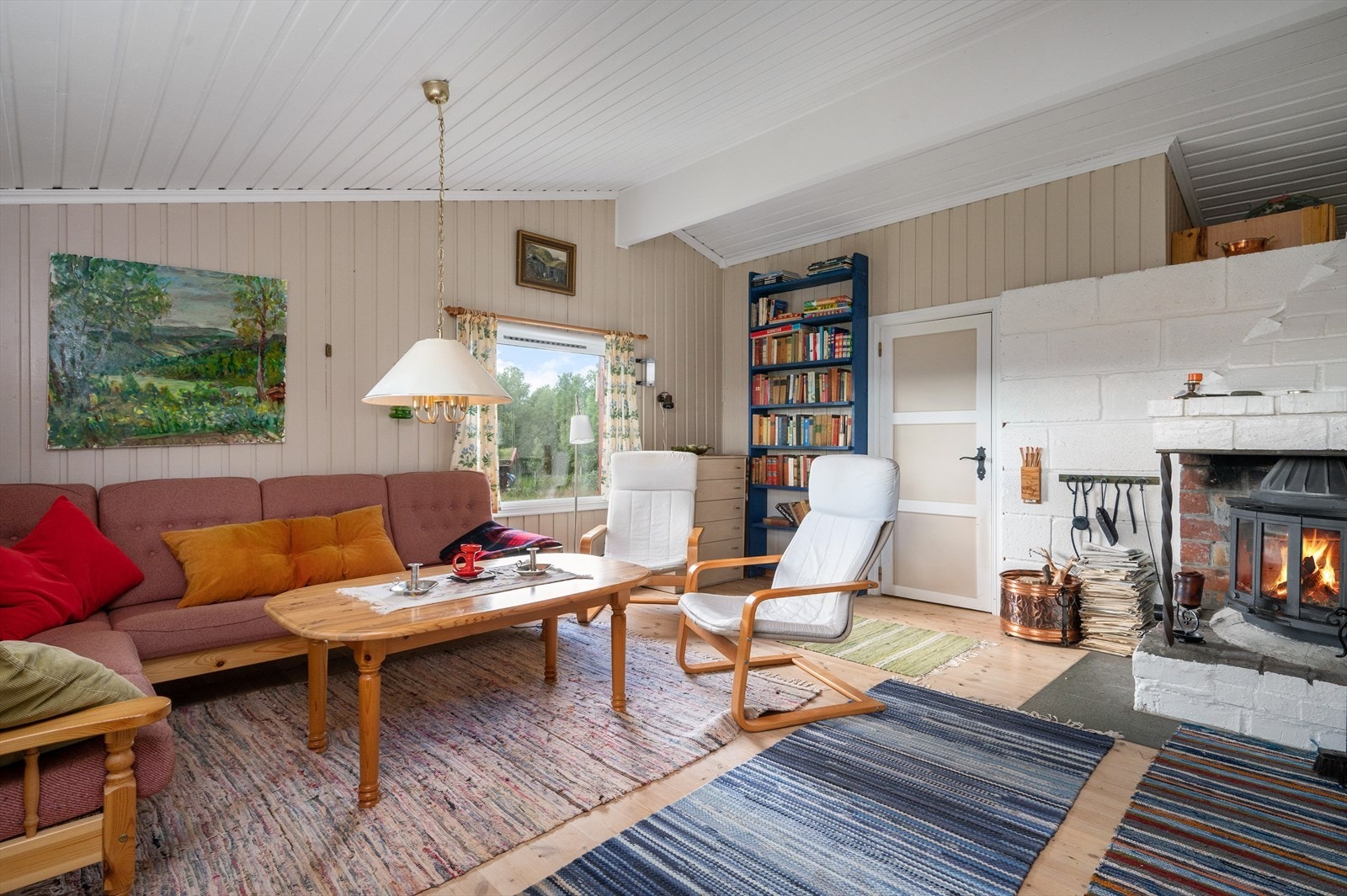 Stuen har peis med innsats som gir god varme. Legg merke til maleriet på veggen: Eier har malt utsikten fra hytta (medfølger ikke) ! Galleribilde